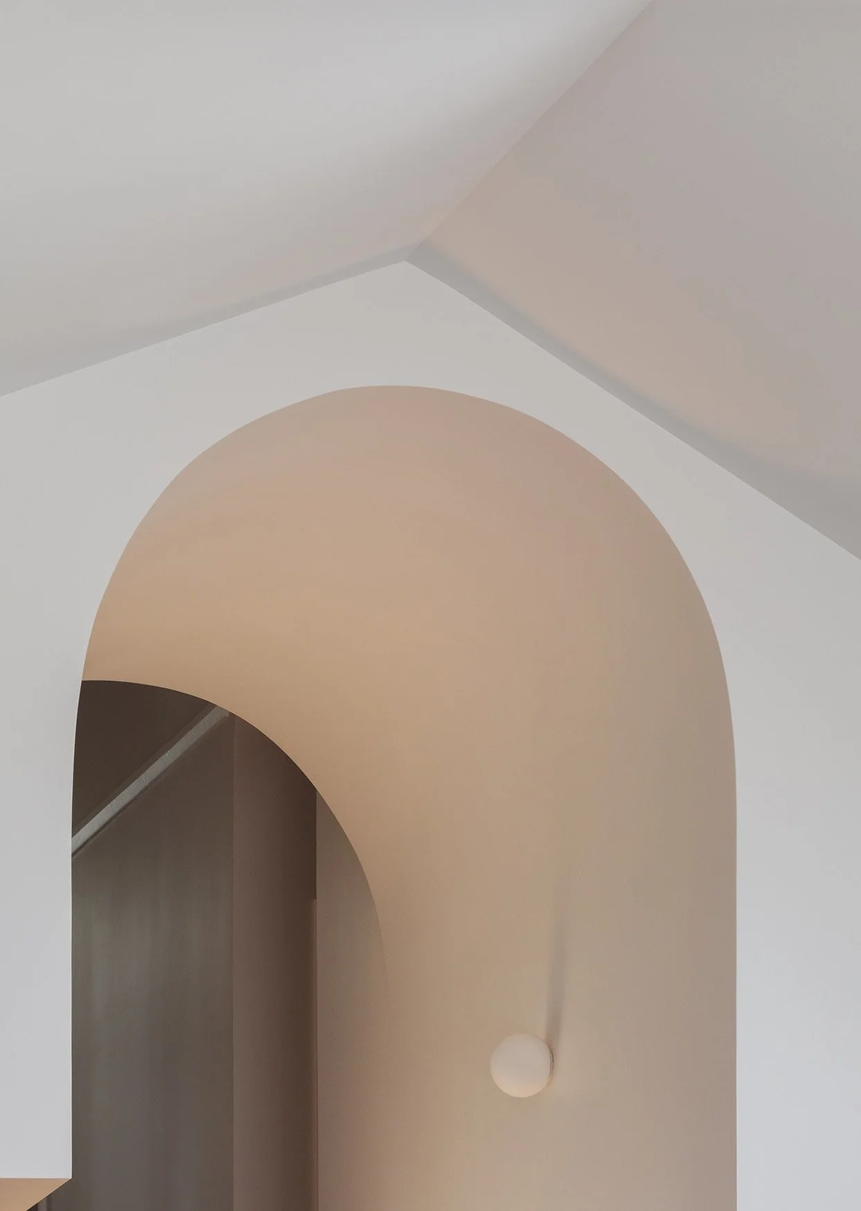 Interior view of a modern space with rounded archways and a white pendant light hanging from the ceiling.