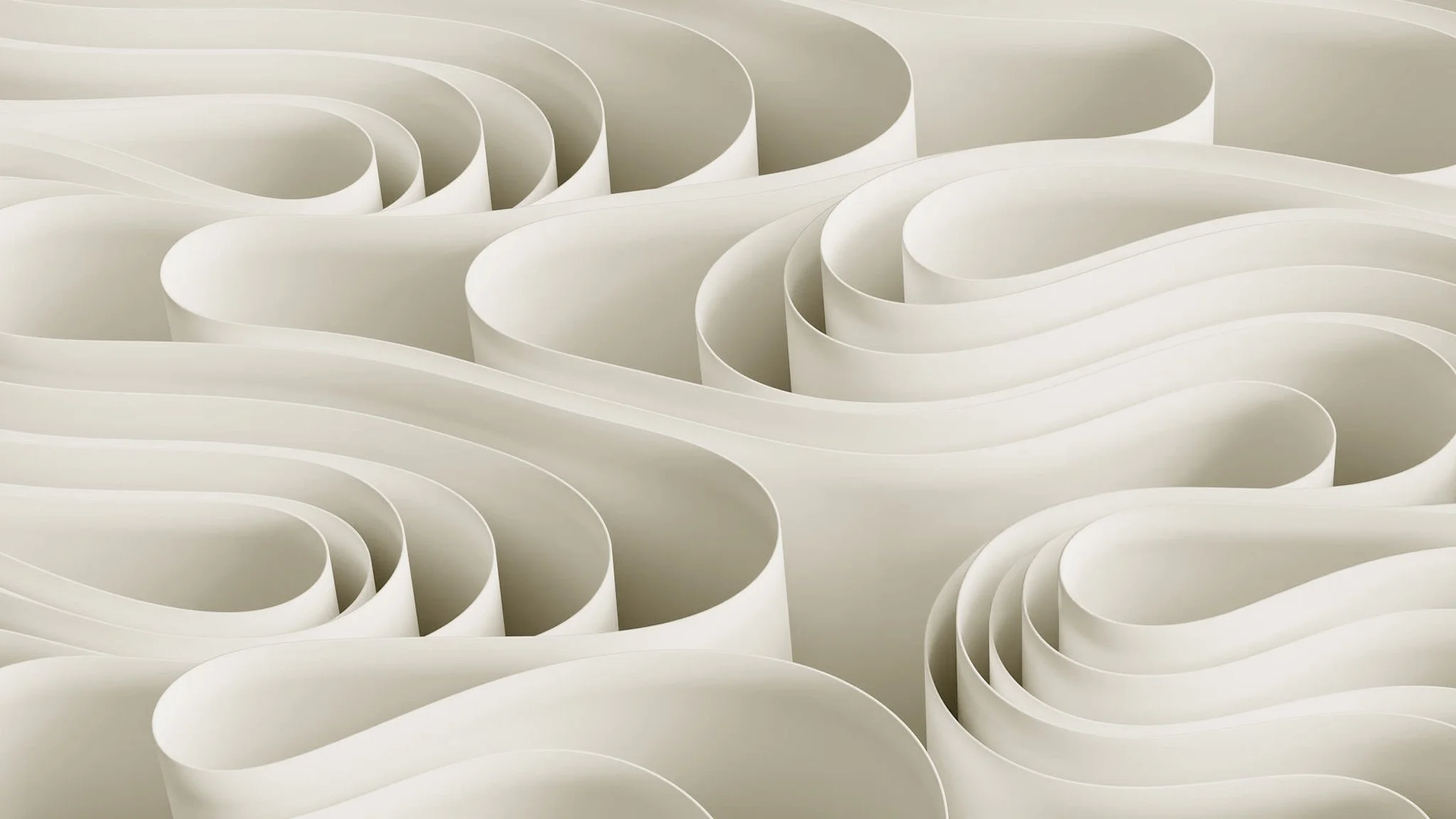 Close-up view of an abstract sculpture made of layered white, curved, ribbon-like shapes creating a flowing, wave-like pattern.