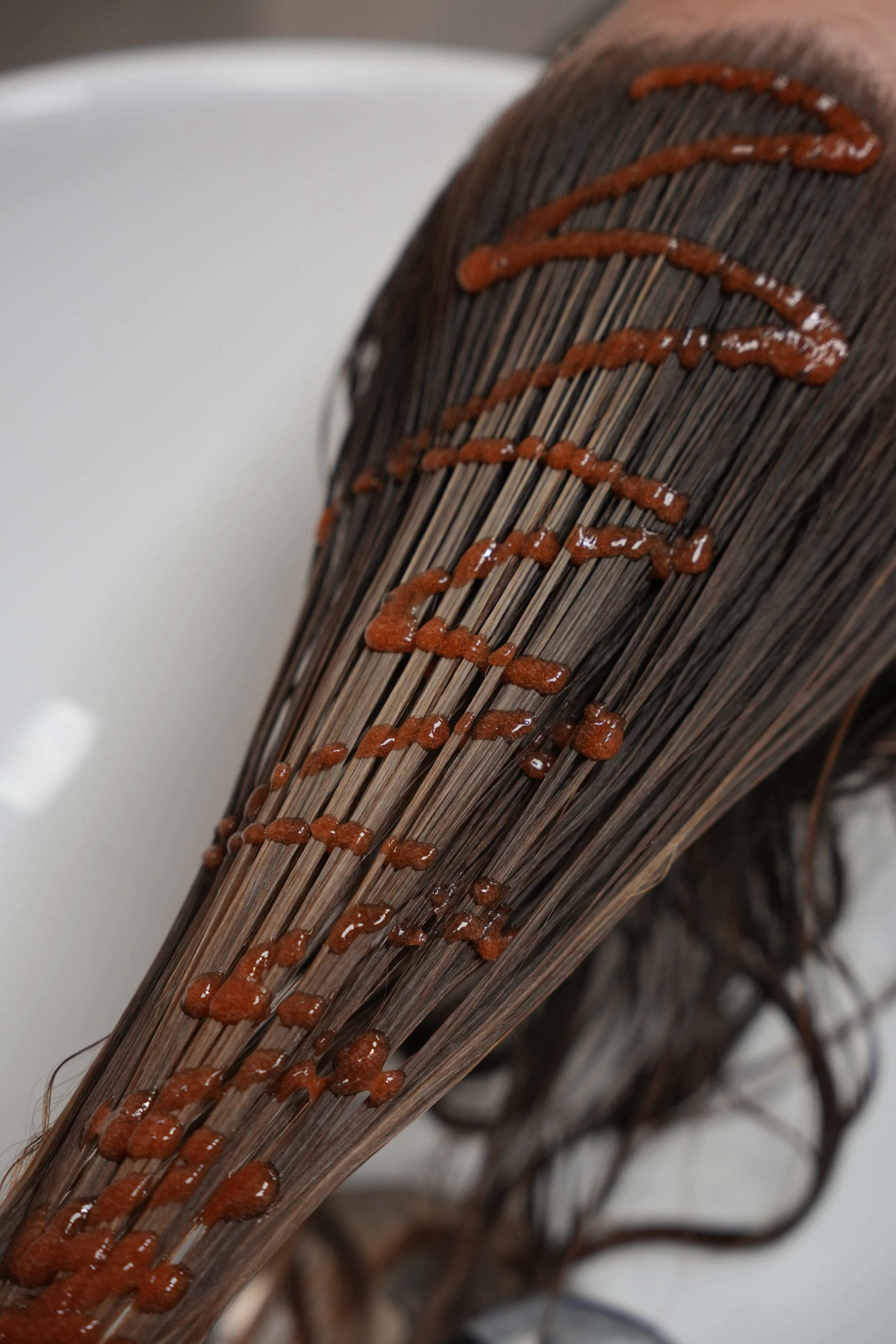 Hair with wet brown strands and streaks of brownish-red hair dye.