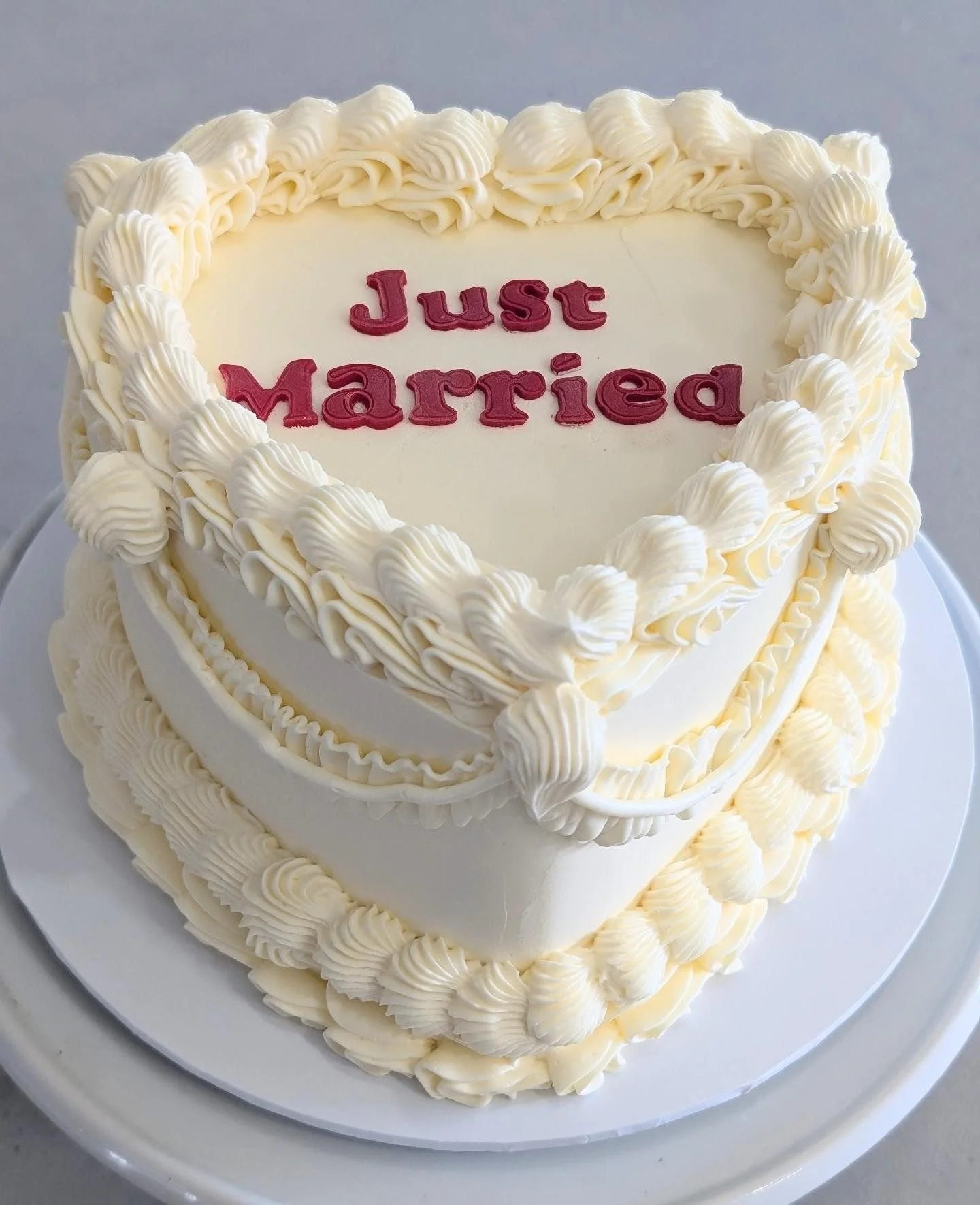 A heart-shaped wedding cake decorated with white icing, with the words "Just married" written in pink on top.