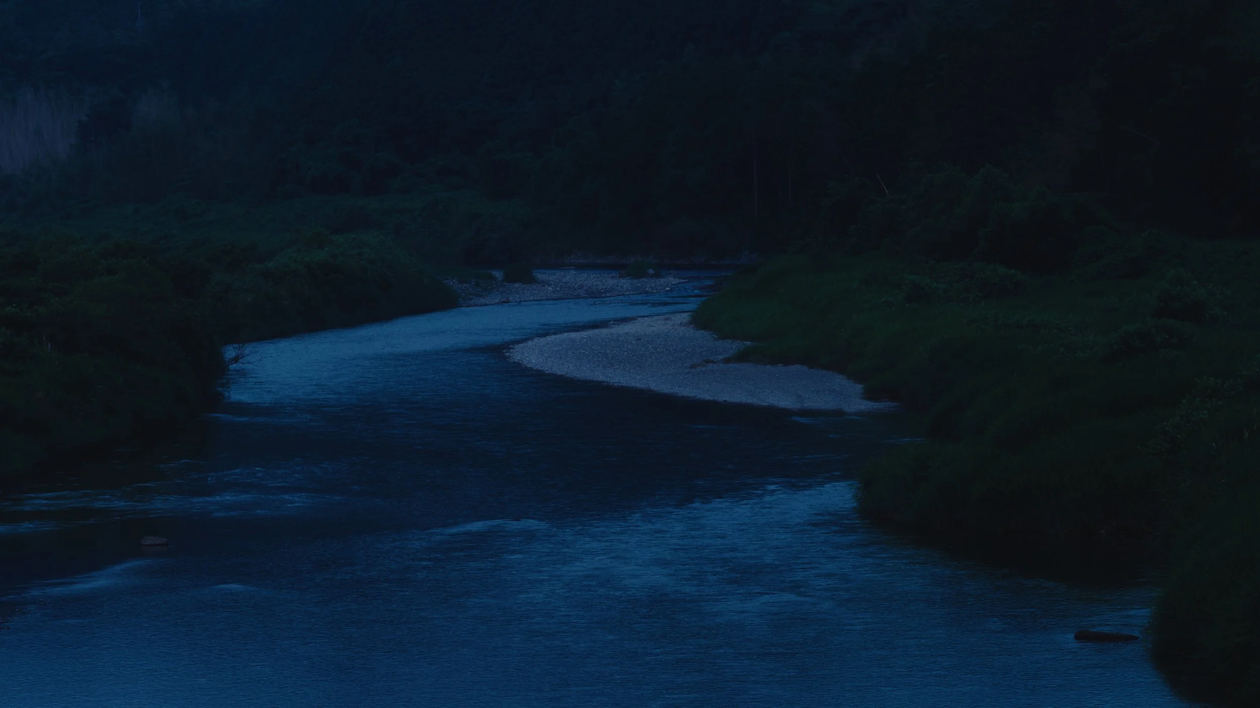 暗くなる前の静かな川と緑の山々の風景