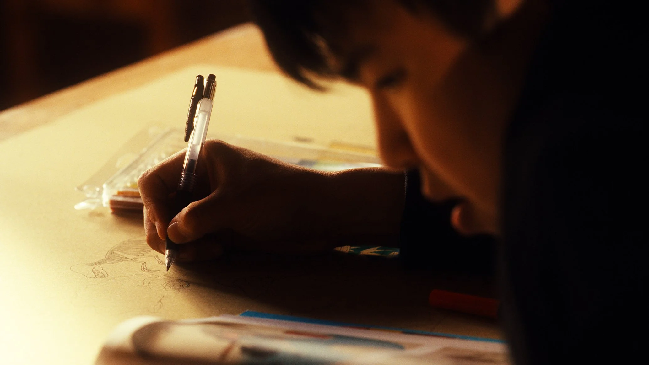 人がテーブルで絵を描いている。