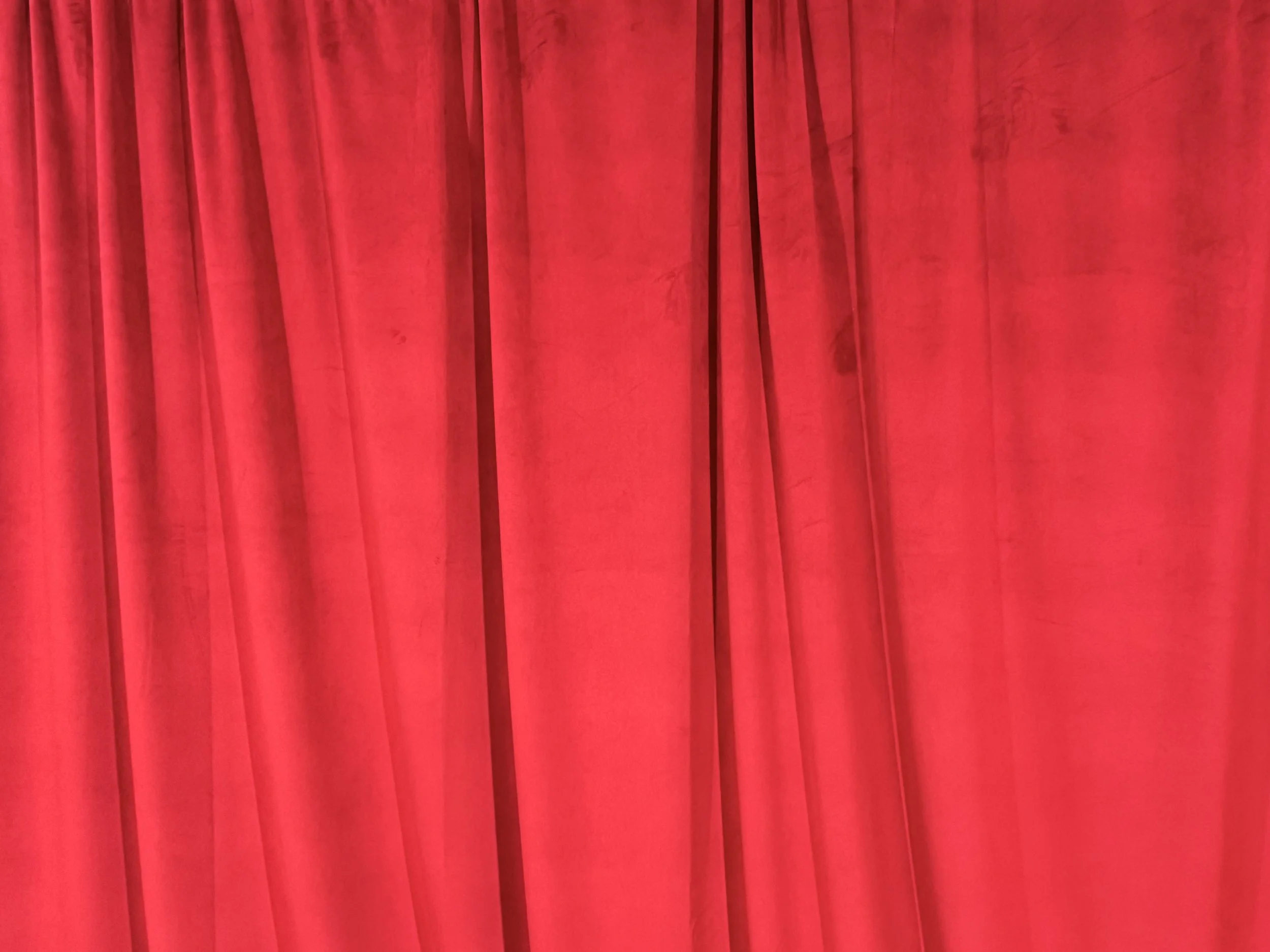 red velvet backdrop. Red stage curtains hanging with slight folds.