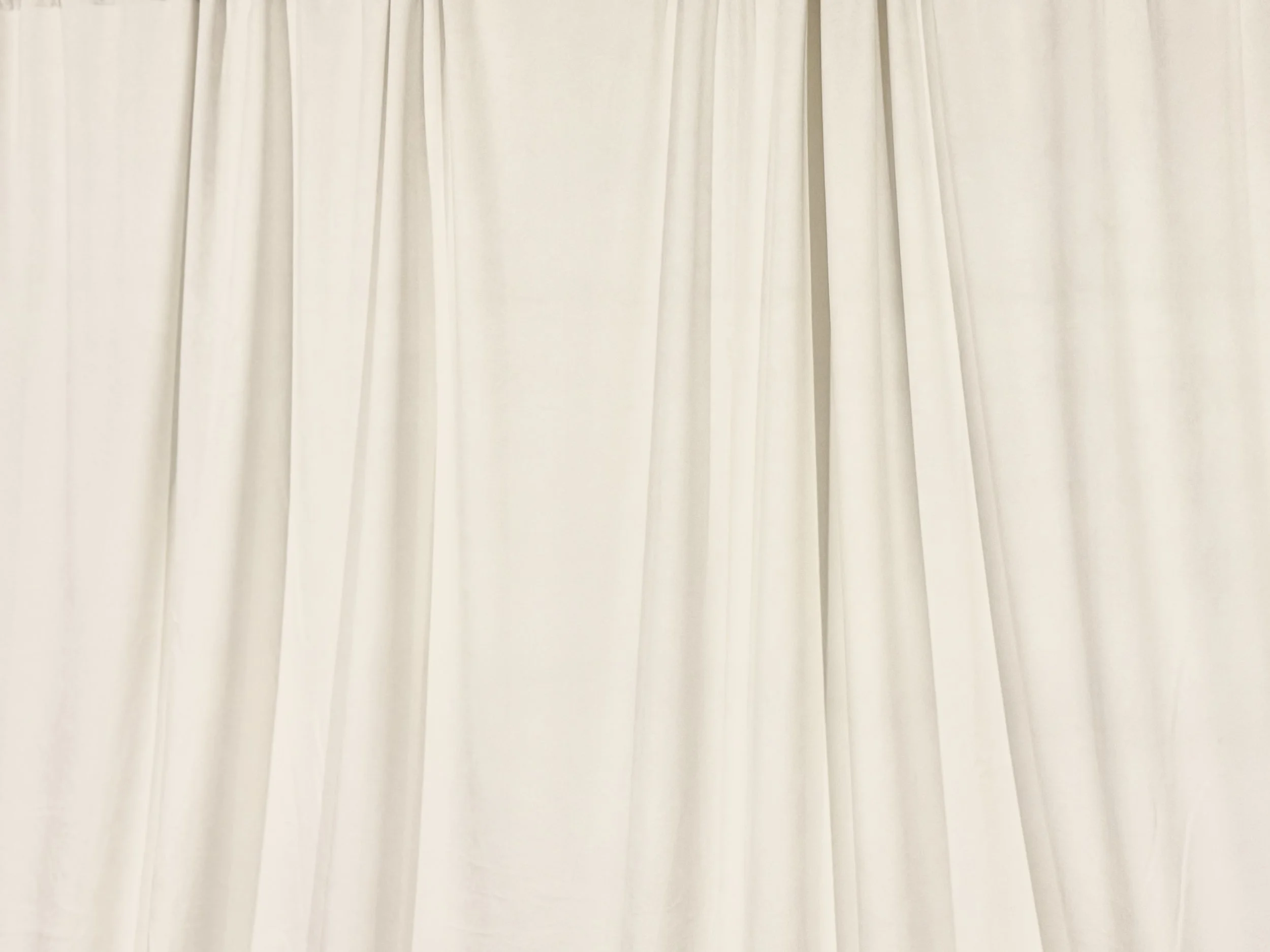 White velvet backdrop. Cream-colored curtains hanging in pleated folds.