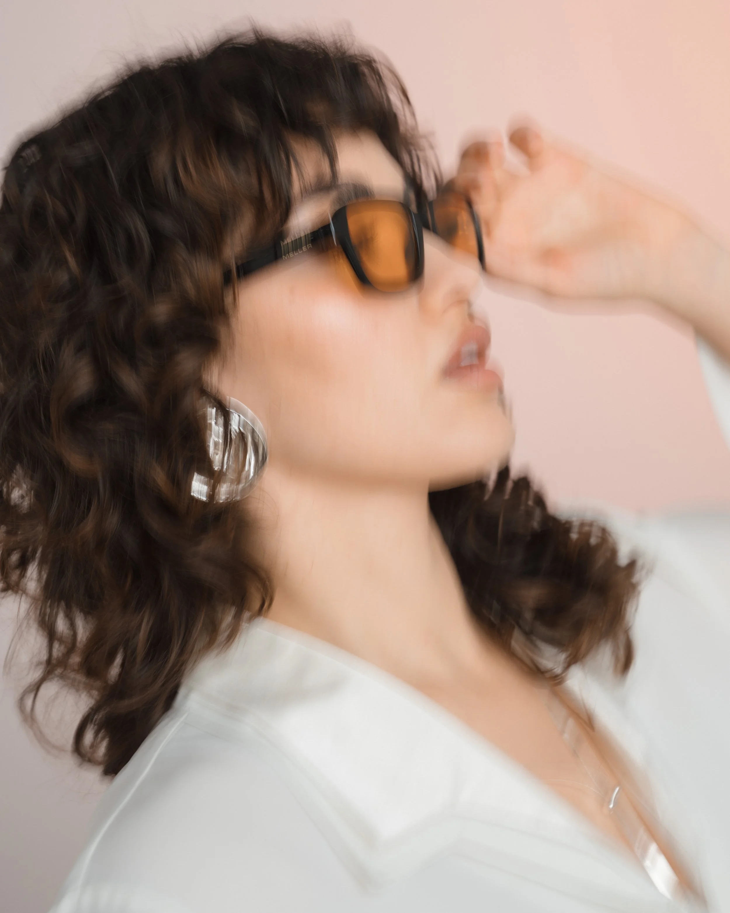 Editorial Portrait einer Frau in Bewegung mit Sonnenbrille im Studio und natürlichem Licht