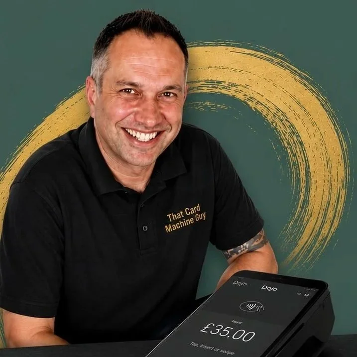 A man smiling, wearing a black polo shirt with the text 'That Card Machine Guy', sitting at a table with a contactless payment device showing a payment of £35.00.