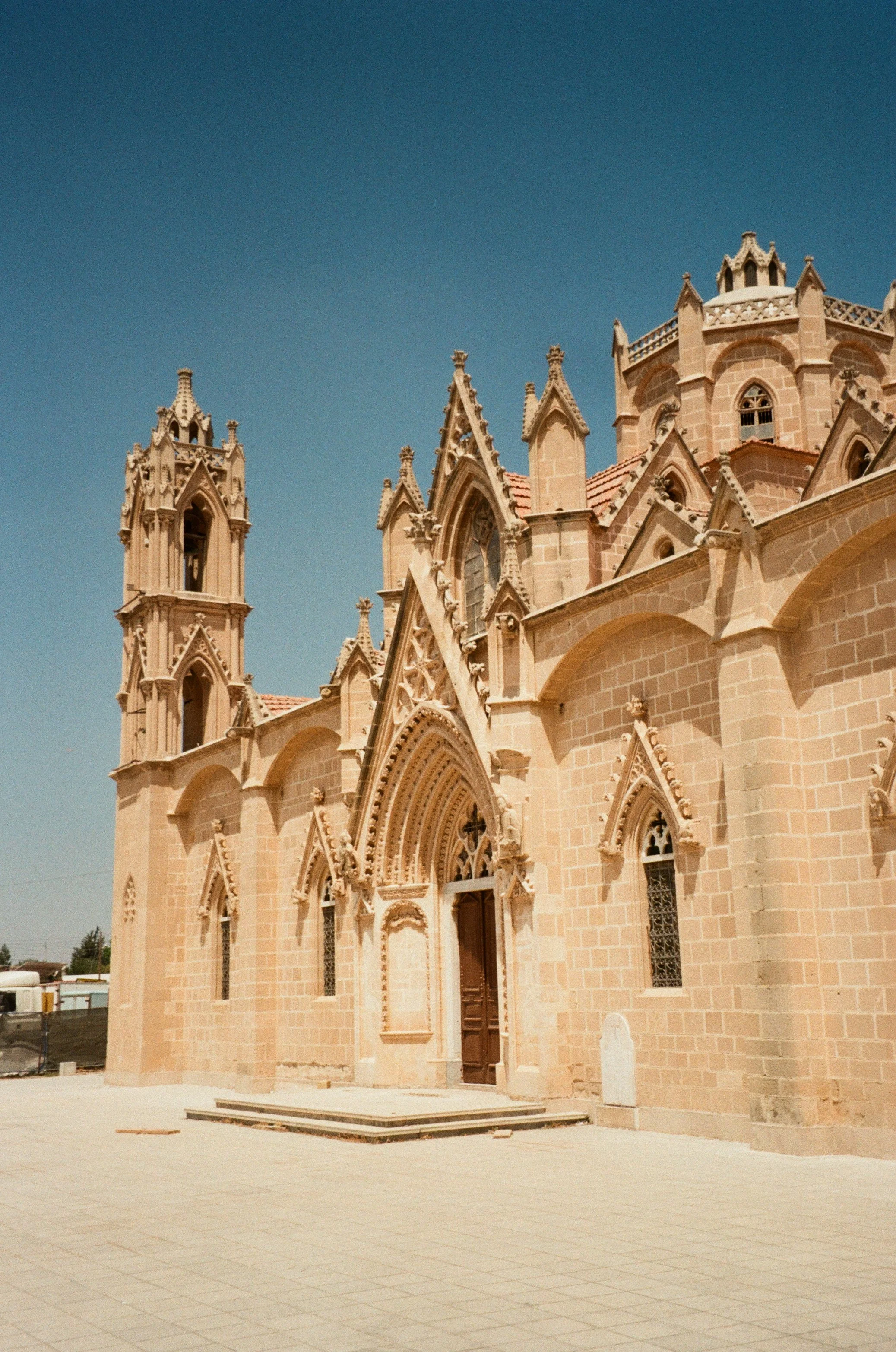 Gothic-style stone church with pointed arches and tall towers under a clear blue sky.
