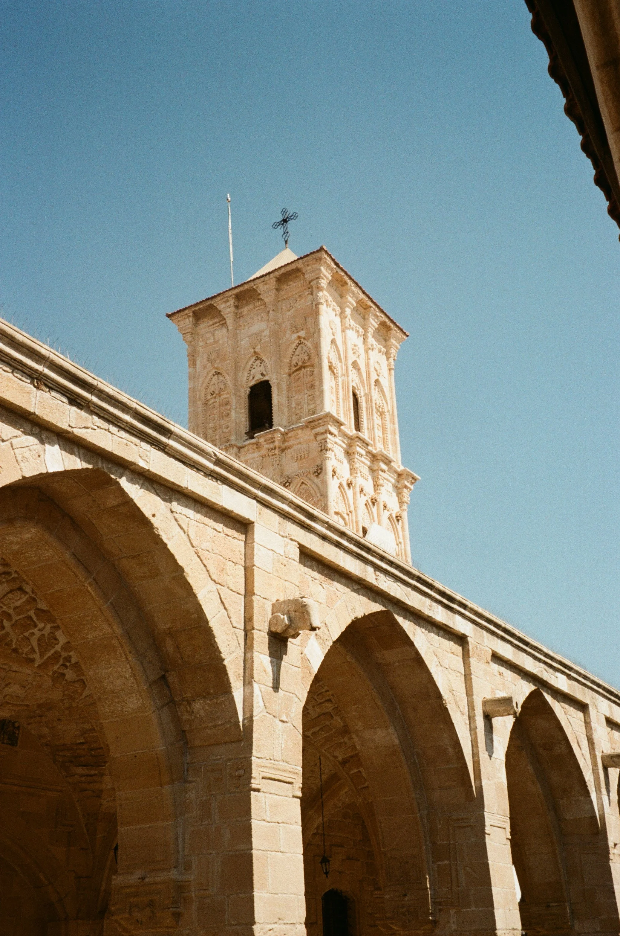 A historic stone building with a tower and arches against a clear blue sky.