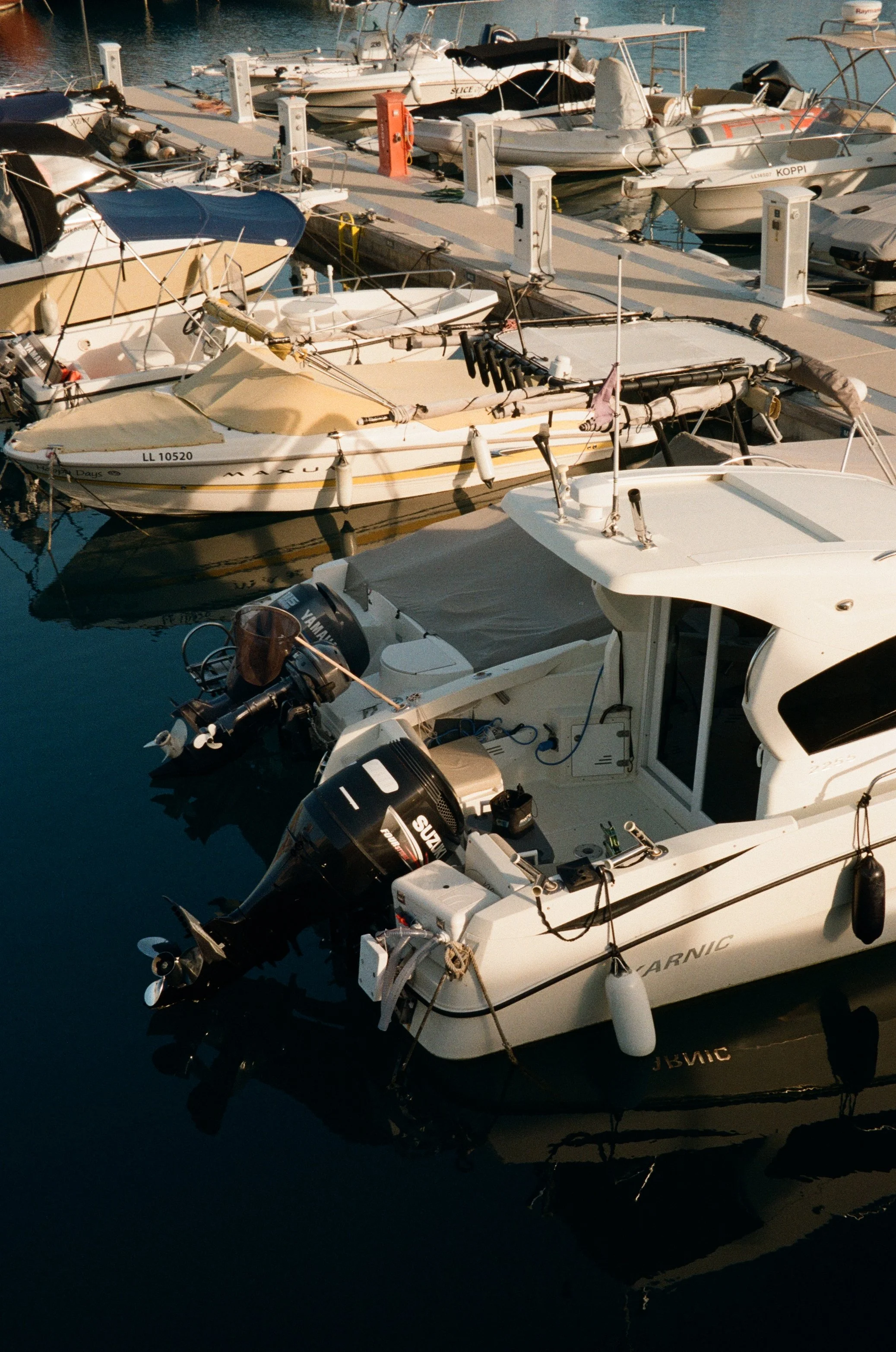 Multiple boats docked at a marina with calm water reflecting the boats.