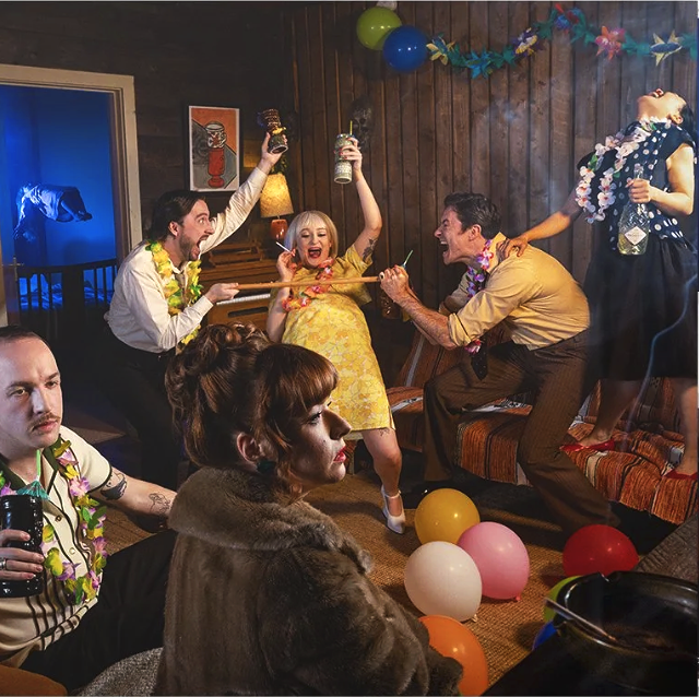 Photo of a group of models celebrating at a party with balloons and colourful decorations, dancing and playing with party props. Record cover for "Soda Blonde' shot in location with great lighting and set design.