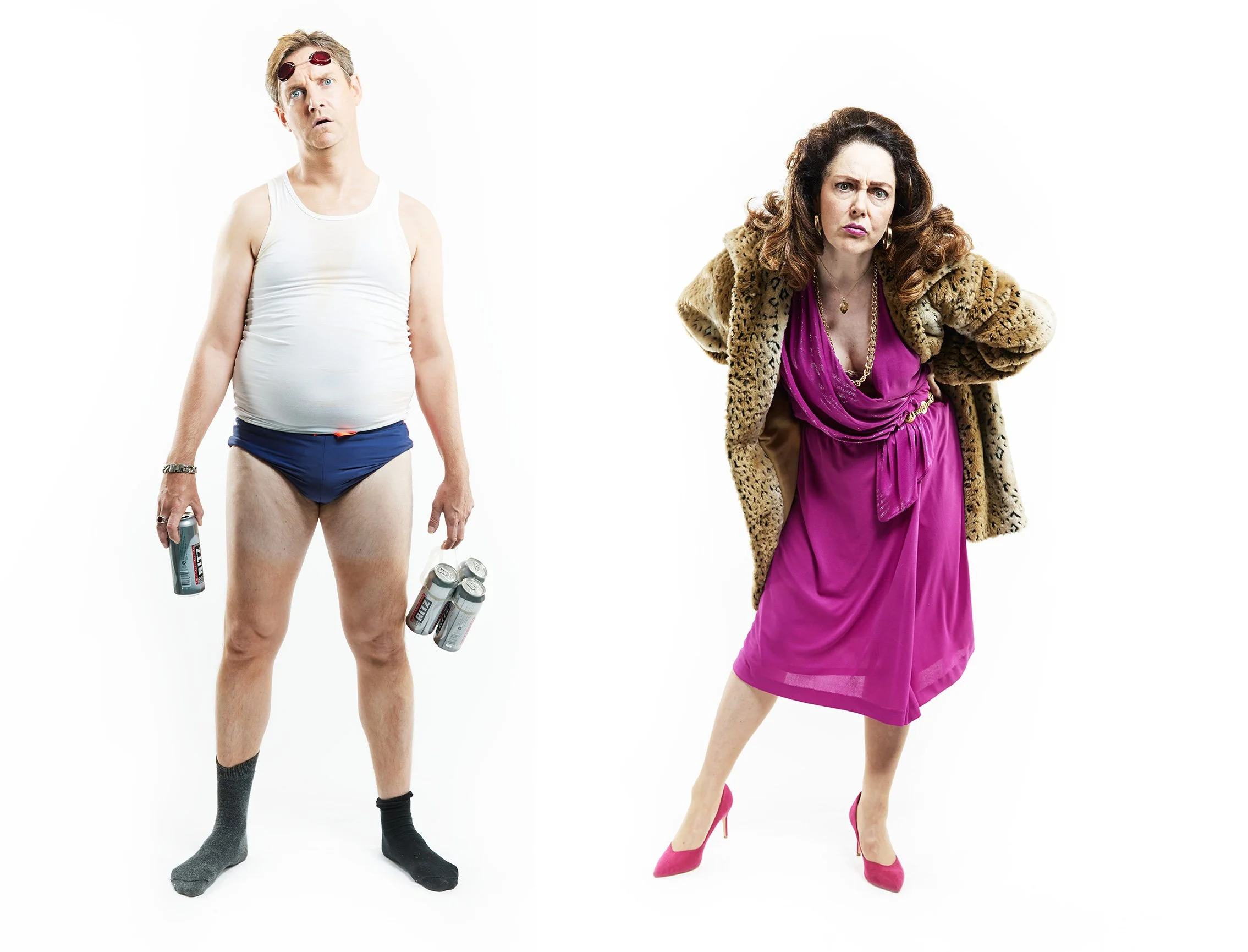 Advertising profession photo taken in studio of a man dressed in underwear holding cans and a woman in a pink dress and leopard coat showing an annoyed expression.
