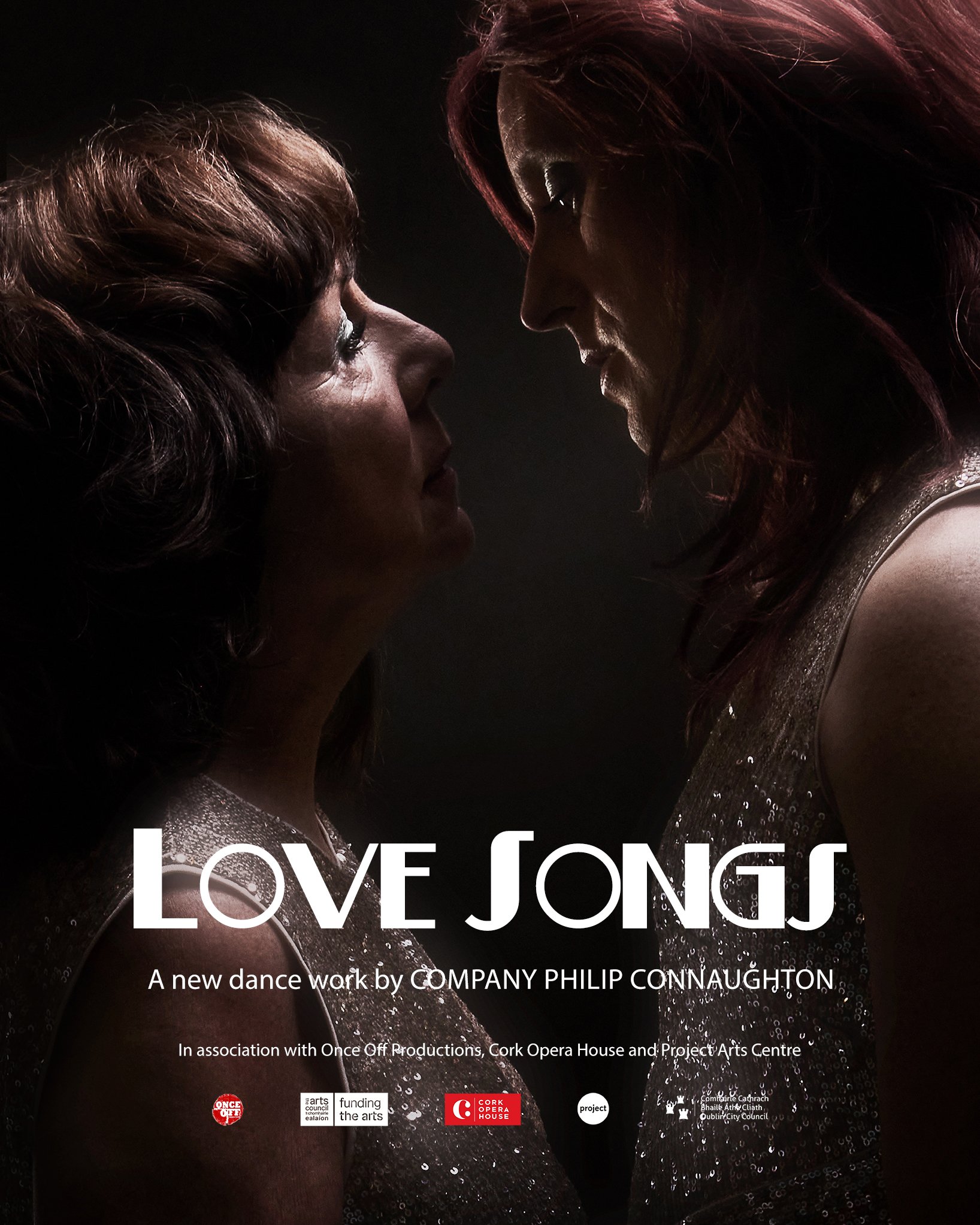 Promotional professional image of two women face each other closely, looking into each other's eyes, with a dark background and subtle lighting highlighting their profiles. They are wearing sparkly tops, showing strong feelings and connection.