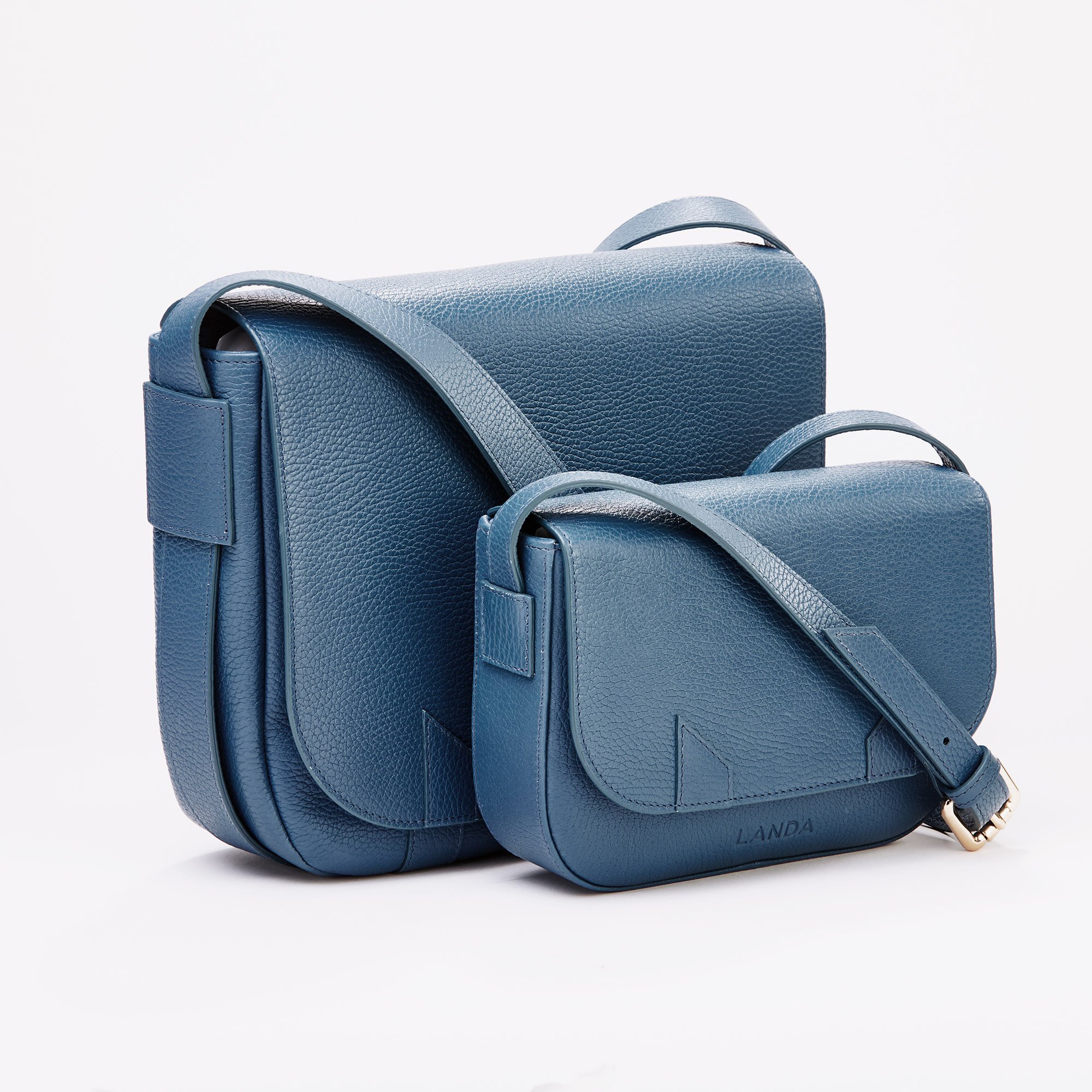 High end advertising profession product photo taken in studio of a two blue leather handbags of different sizes, placed against a white background.