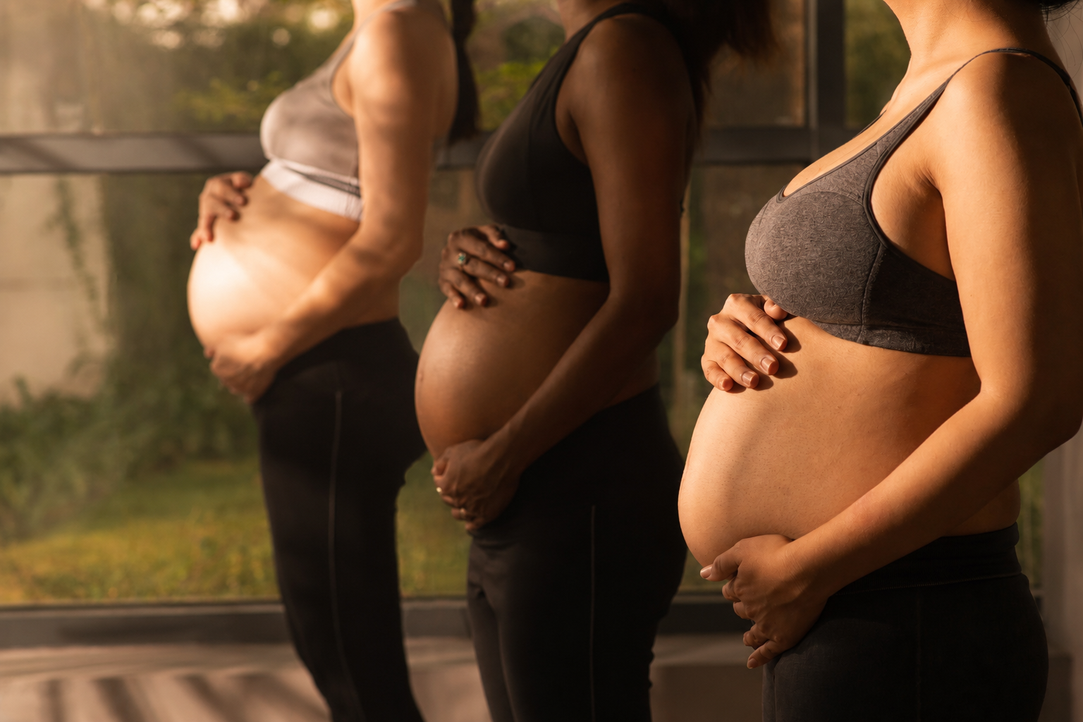 groupe de femmes enceintes avec leurs main sur le ventre en cours de yoga prenatal