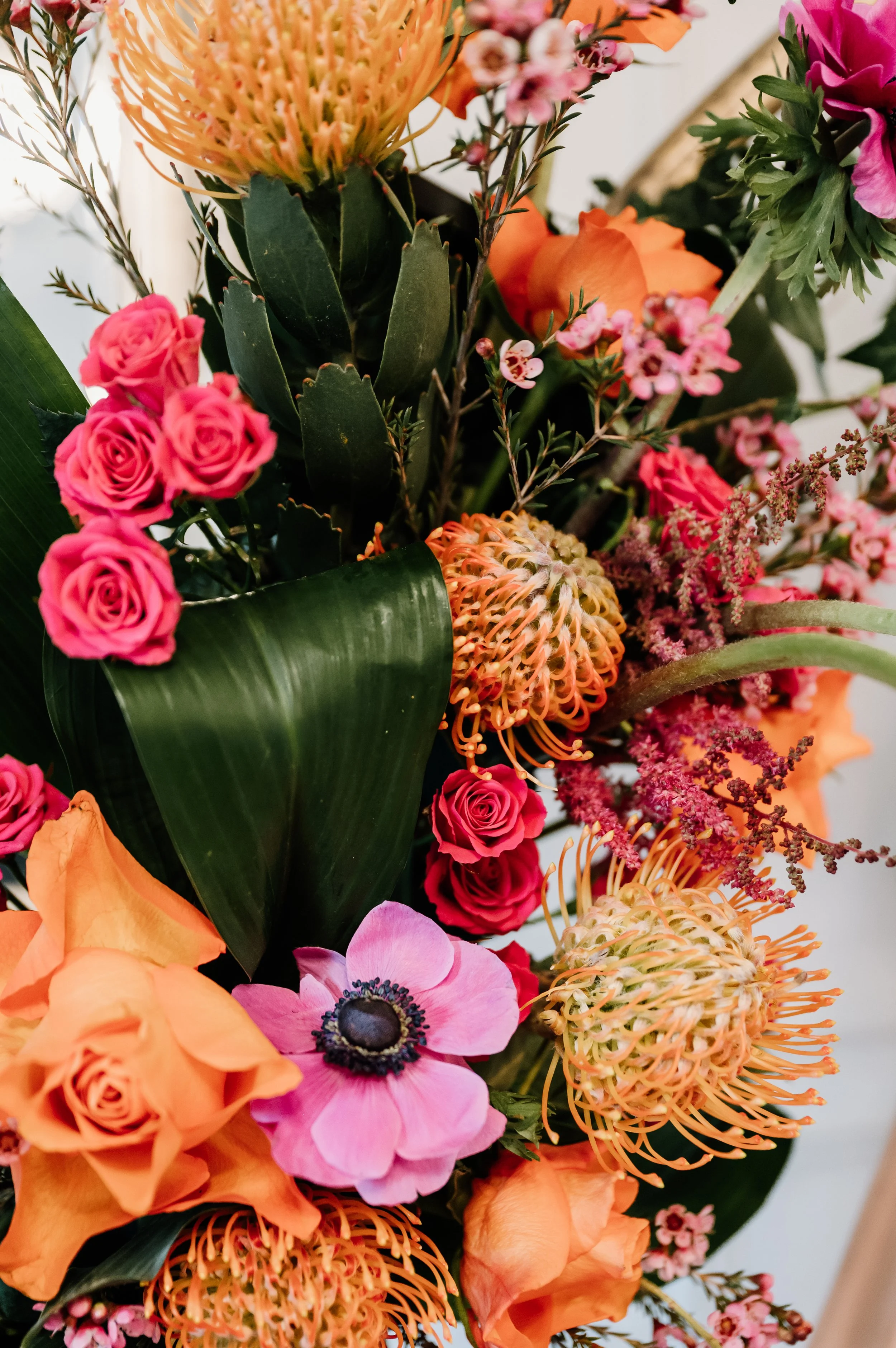 A vibrant bouquet of various flowers including pink roses, orange roses, pink anemone, peach-colored roses, and various greenery and filler flowers. East Yorkshire based wedding florals, handcrafted wedding flowers.