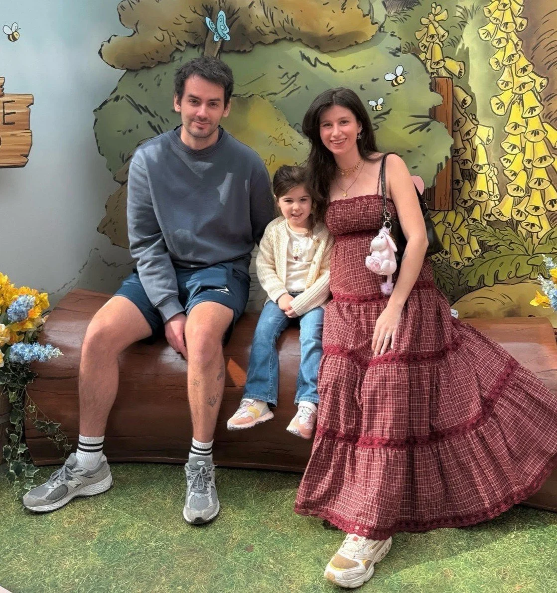 James, Chloe and Athena sitting on a log at the Winnie the Pooh avert in London for a Disney Collabaration