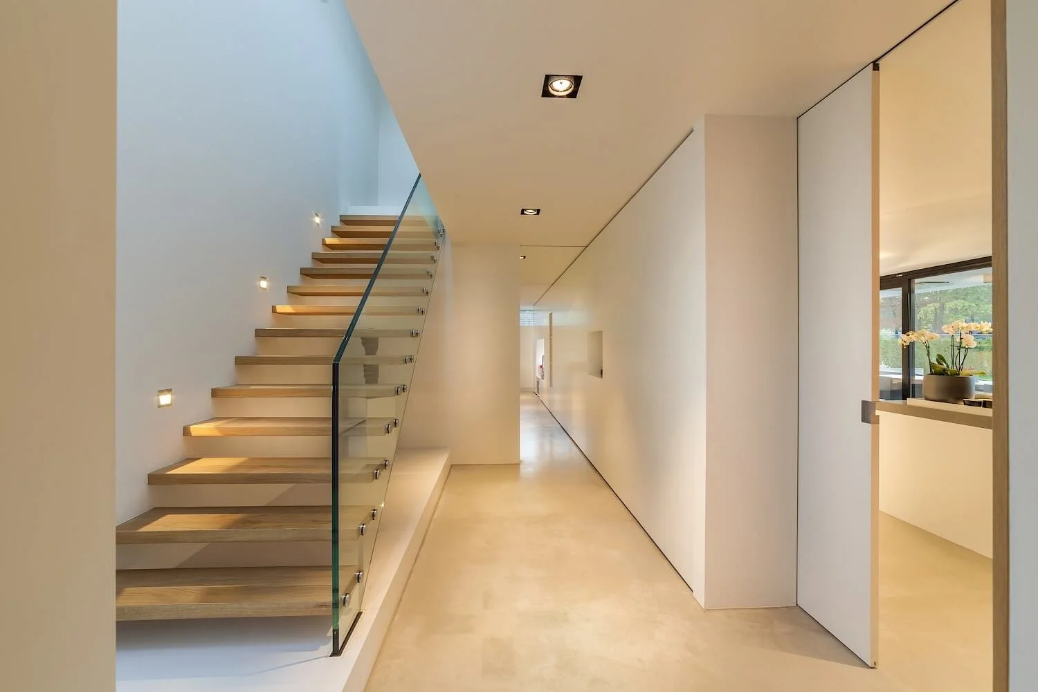 Interieur van een modern, minimalistisch huis met een houten open trap en witte muren