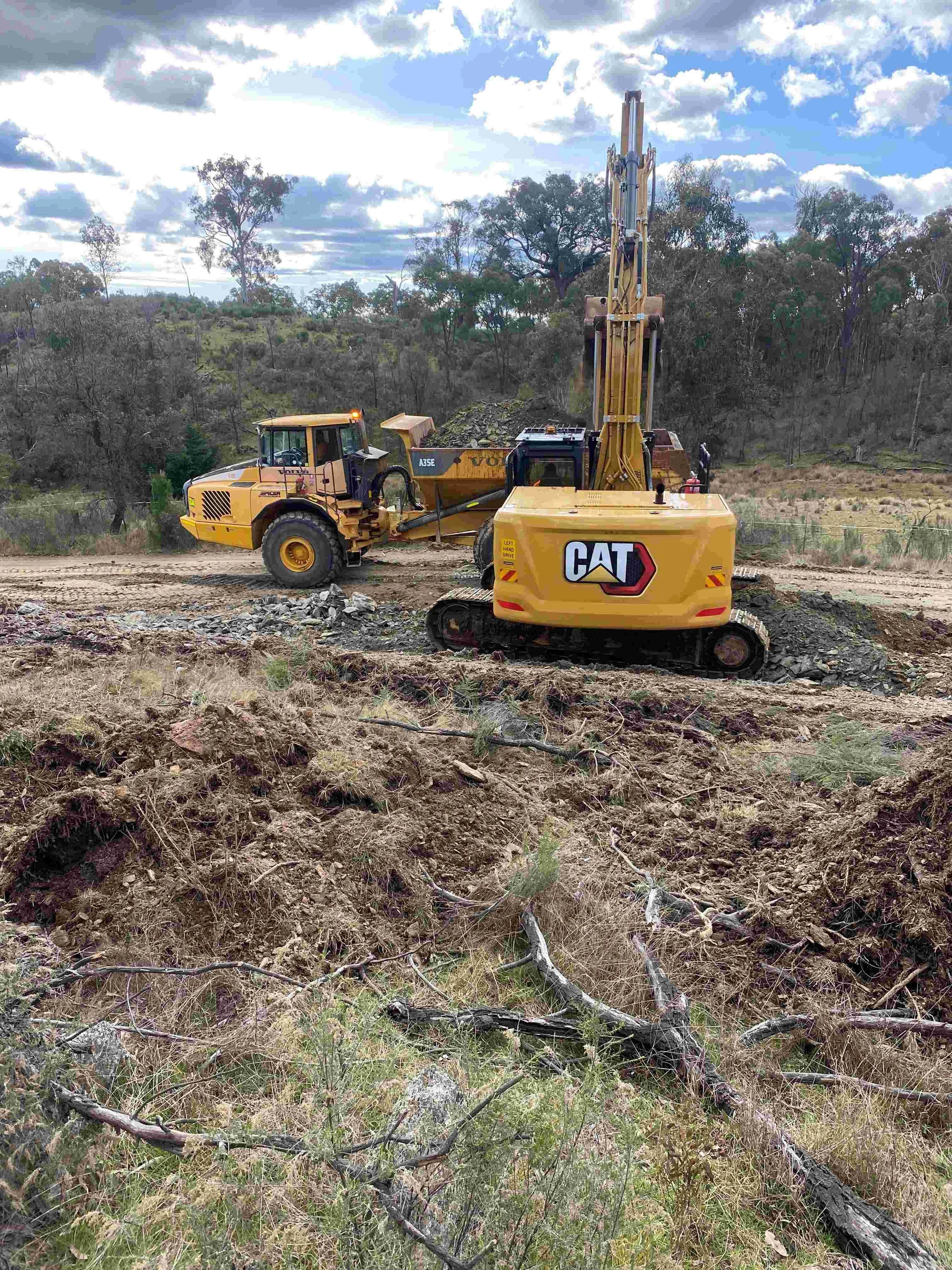 Excavator and dump truck completing bulk earthworks and material transport on construction site