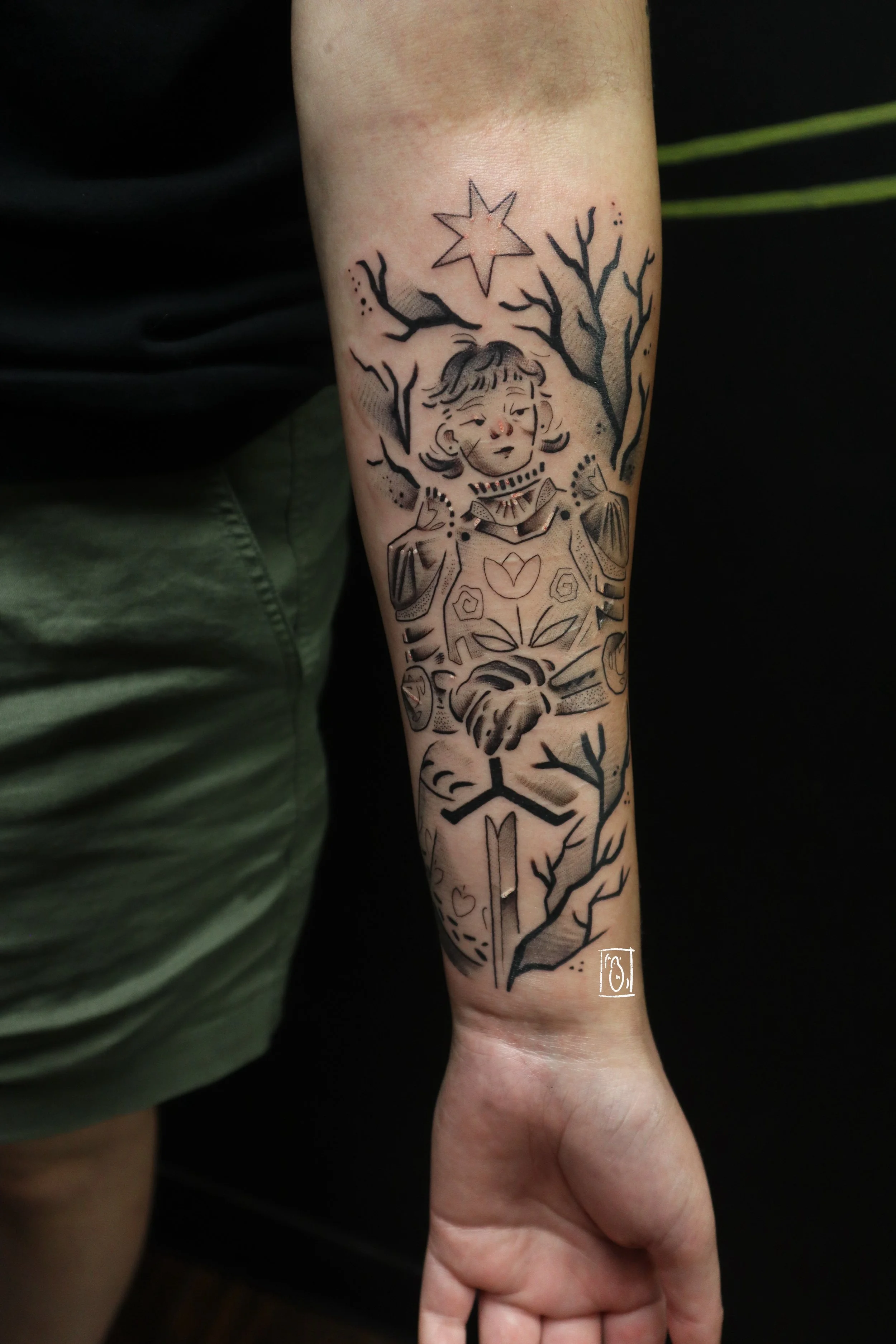 tattoo of an androgynous knight. they rest their hands atop the hilt of a sword and are framed by a thicket of thorns. it is on the inside of a forearm