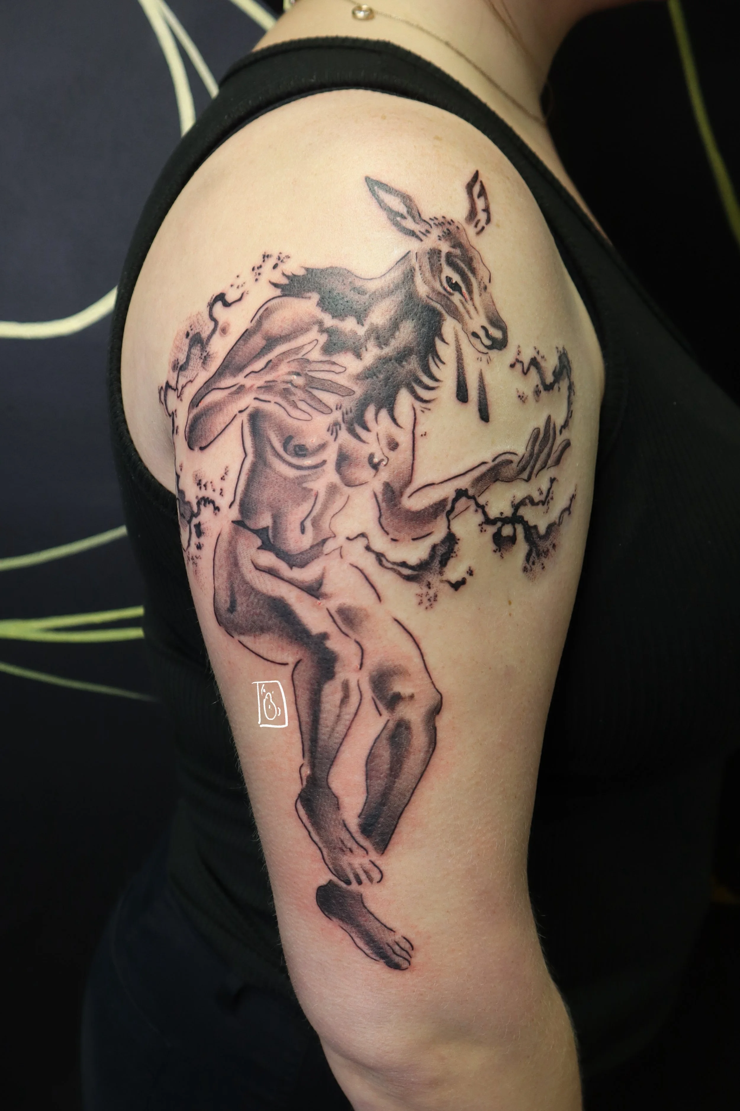 tattoo interpretation of the elk headed woman from stephen graham jones' book. her head is a doe elk, tears dripping from her face, and her body is humanoid. from a rough incision in her stomach flows black ichor. on the client's upper arm