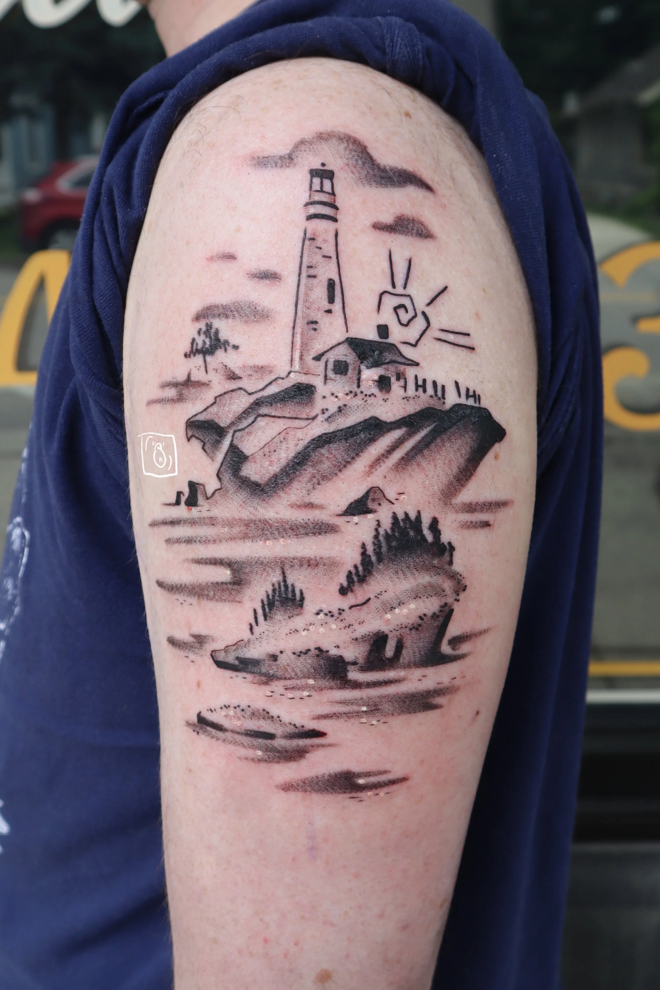 tattoo of a lighthouse scenescape. the focus is on the ocean and the small islands, with the lighthouse being tucked more into the background. done in a soft black and grey on the outside of an upper arm