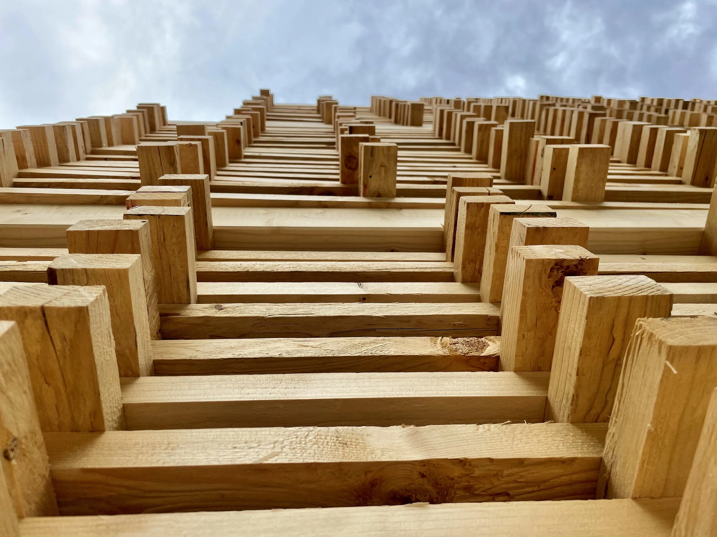 Nahaufnahme eines Holzpalettenstapels mit Blick nach oben auf den Himmel.