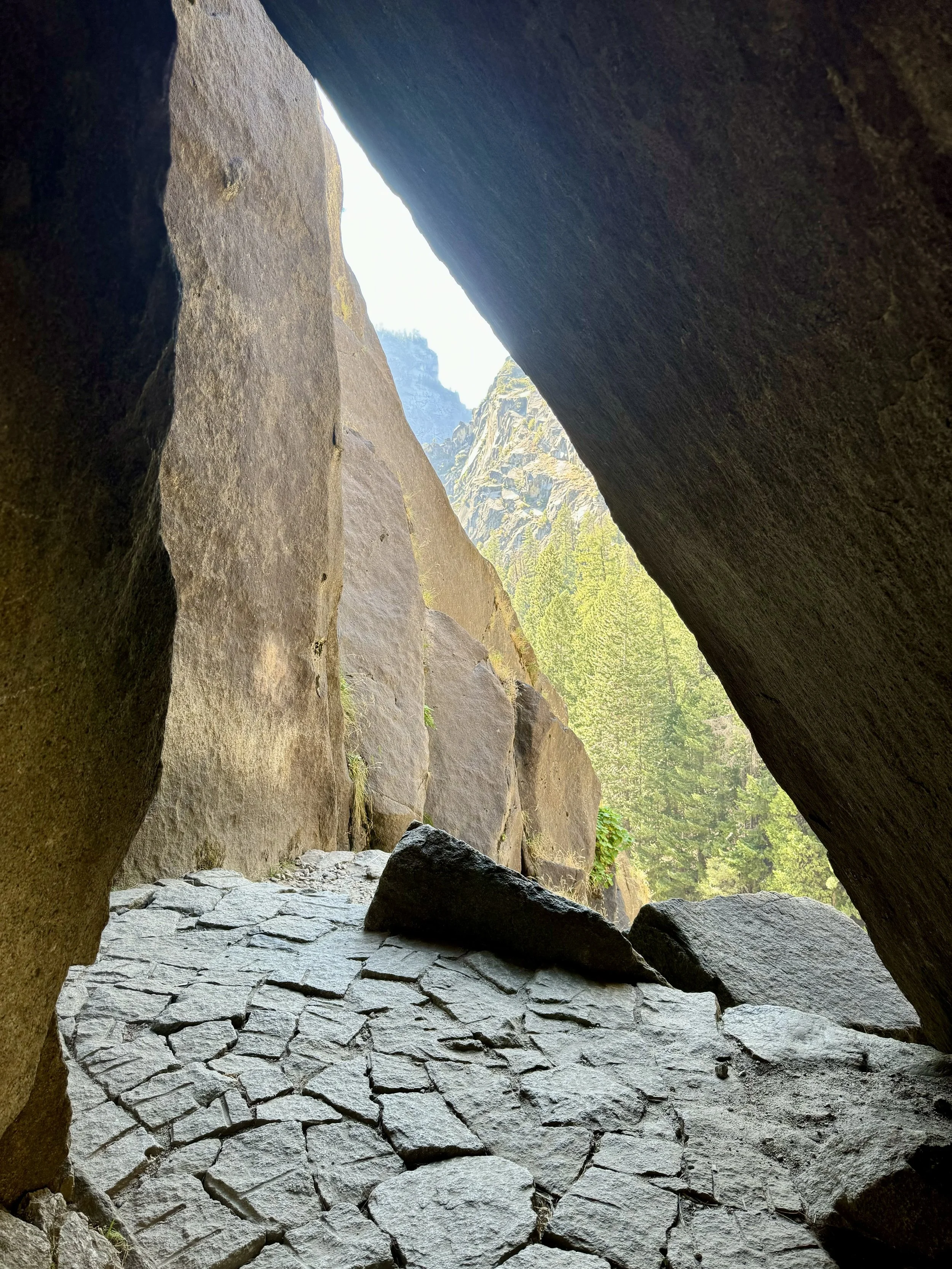 Blick aus einer Felsspalte auf einen Flussverband, umgeben von grünen Bäumen, mit Bergen im Hintergrund. Wie im Bild kommen in meiner Arbeit als Ärztin mit den Schwerpunkten Psychosomatik und Musikermedizin verschiedene Aspekte integrativ zum Tragen.
