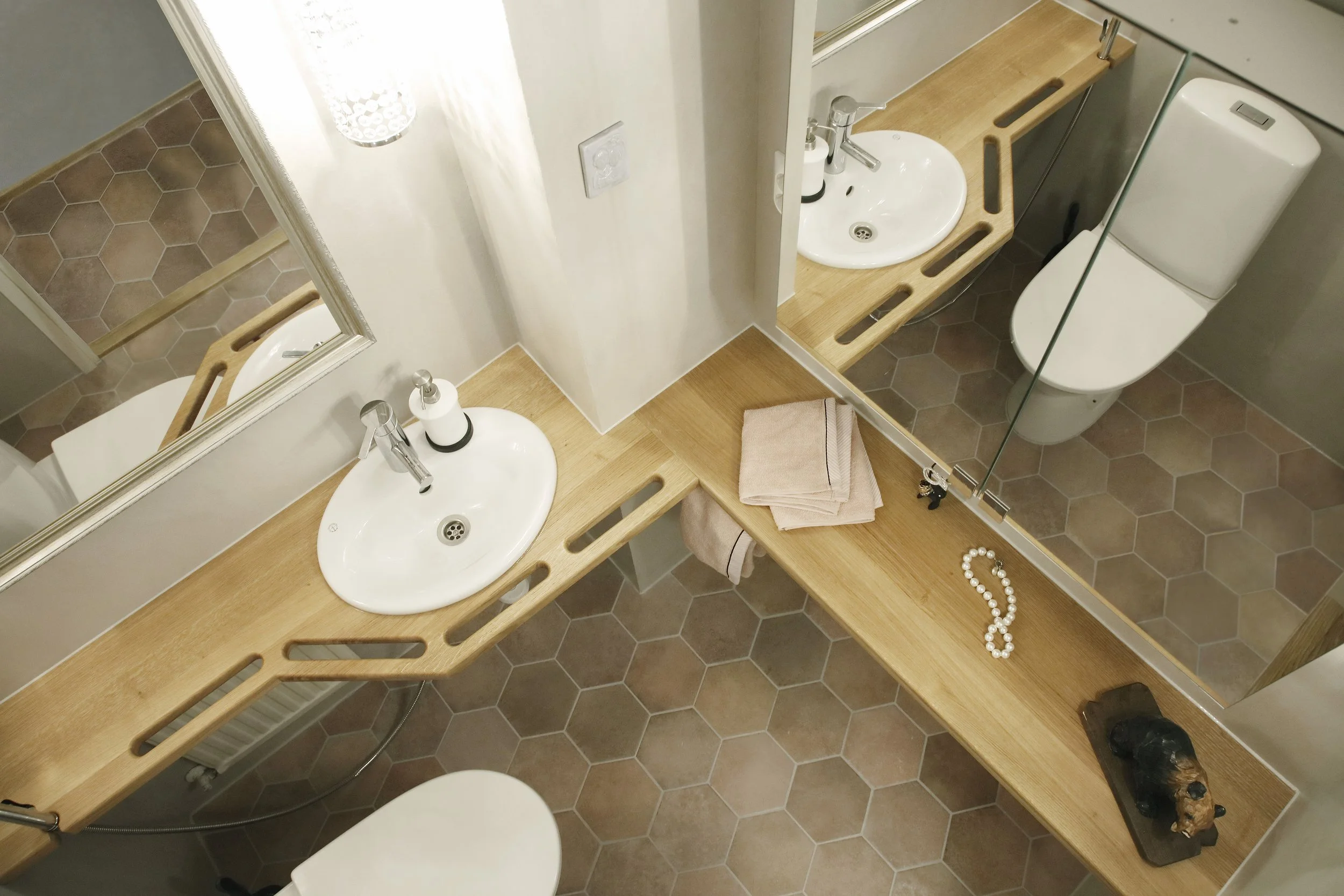 Valaistus kylpyhuoneessa heijastuu peilistä, jossa näkyy pesuallas ja wc-pönttö. Lavuaarintasossa on käsituet, joiden avulla voi nostaa itsensä ylös pöntöltä.