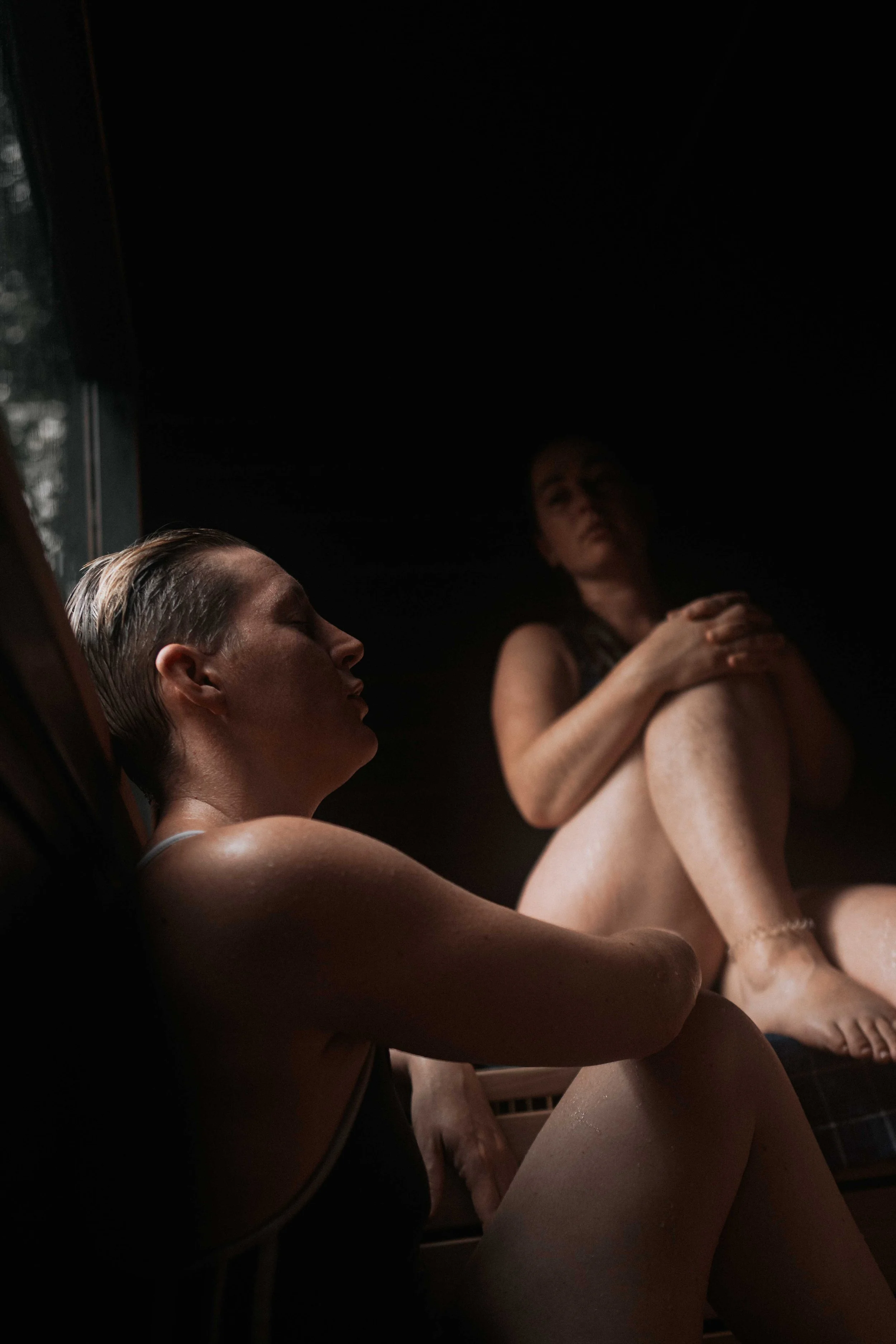 Inside dark sauna. Two people sit in the heat