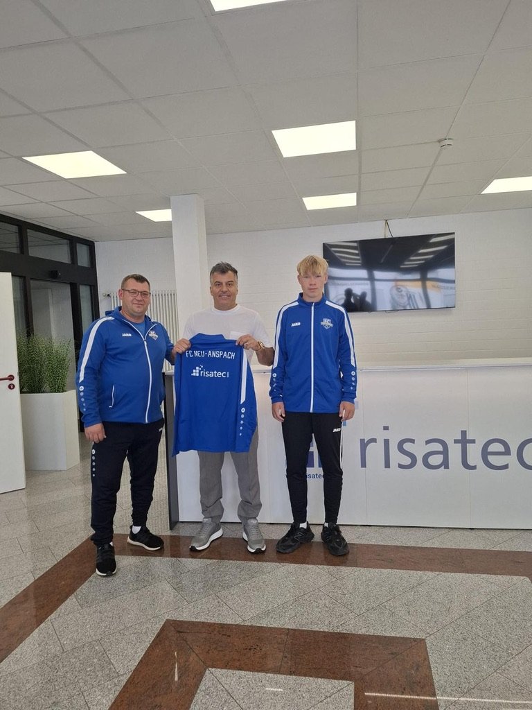 Sponsoring:  Geschäftsführer und Partner präsentieren ein blauen Vereinsjersey  von FC Neu-Anspach und risatec GmbH als Sponsorpartner.