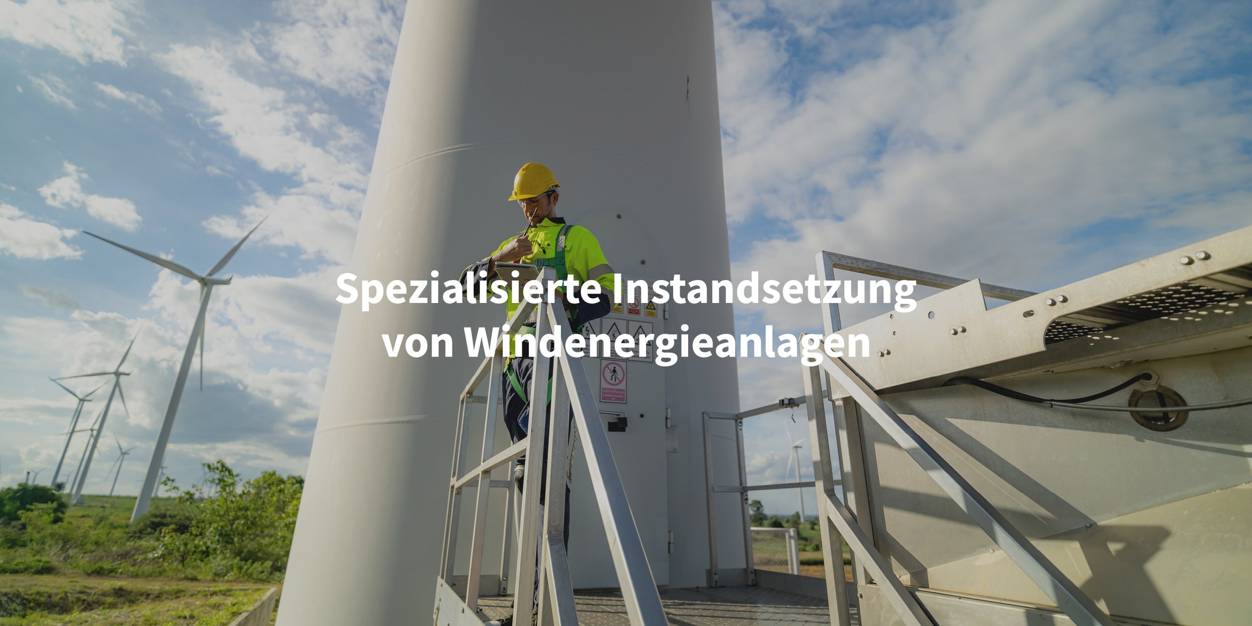 Ein Techniker in Sicherheitsausrüstung inspiziert eine Windturbine auf einem Windpark bei sonnigem Himmel.
