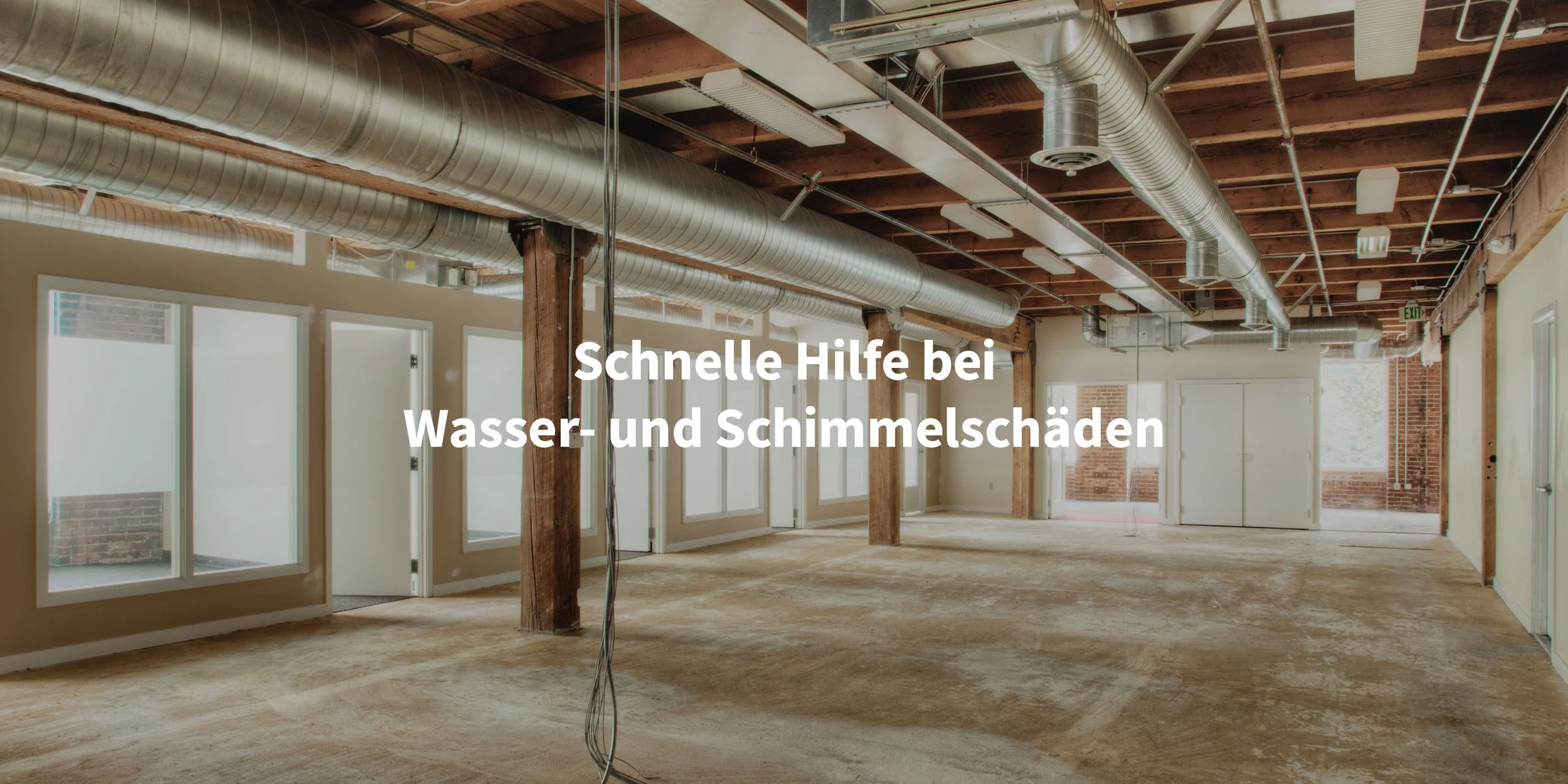 Innenraum eines Gebäudes mit sichtbaren Klimaanlagen- und Belüftungsrohren, großen Fenstern, Holzdecken und unbehandeltem Boden. Text auf dem Bild: Schnelle Hilfe bei Wasser- und Schimmelschäden.