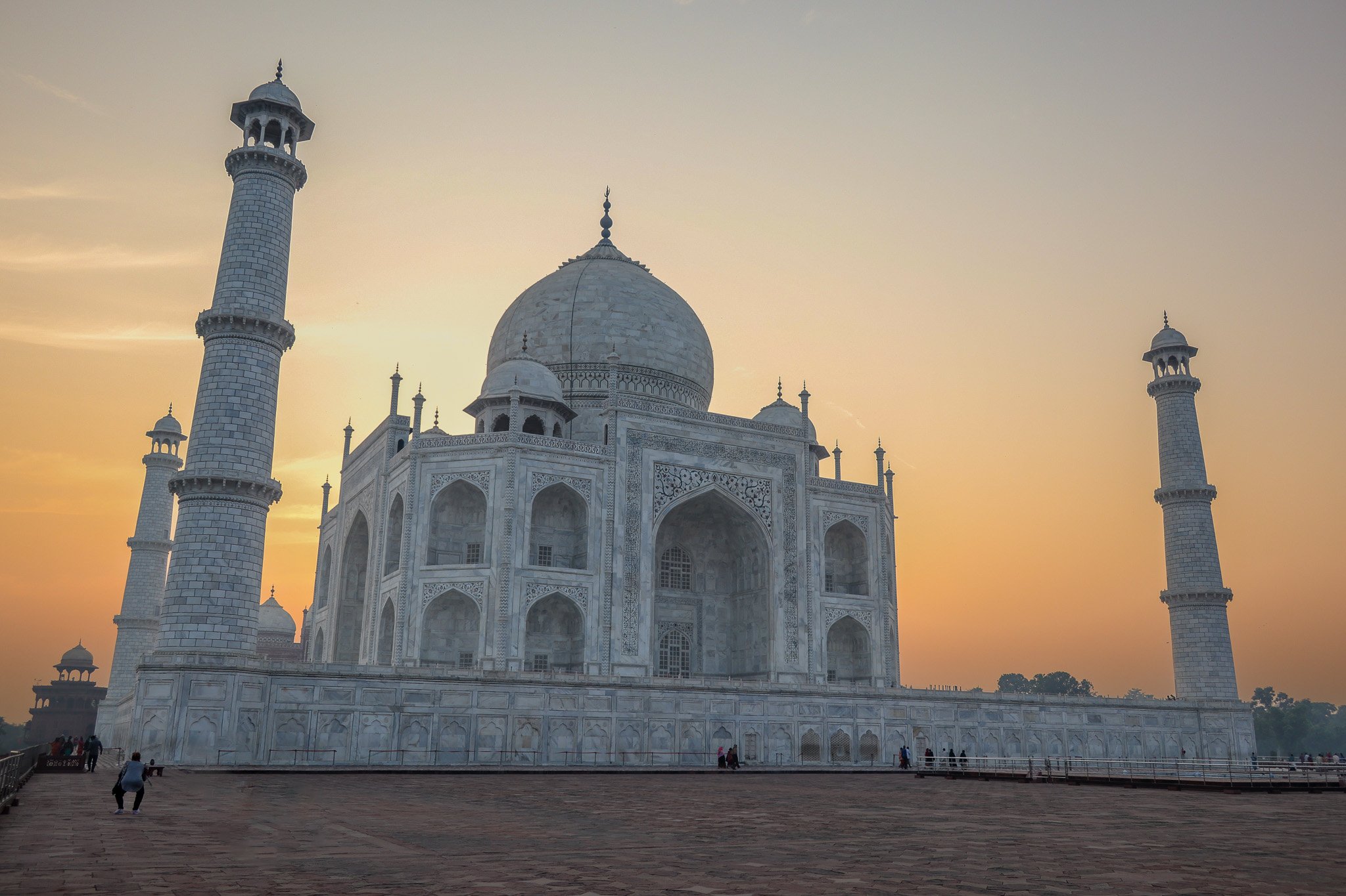 The Taj Mahal at sunset, showing its white marble domes and minarets.