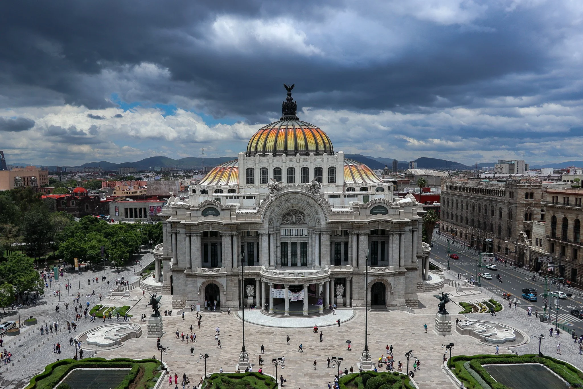 View of the Palace of Bellas Artes in Mexico City with a dark cloudy sky in the background.