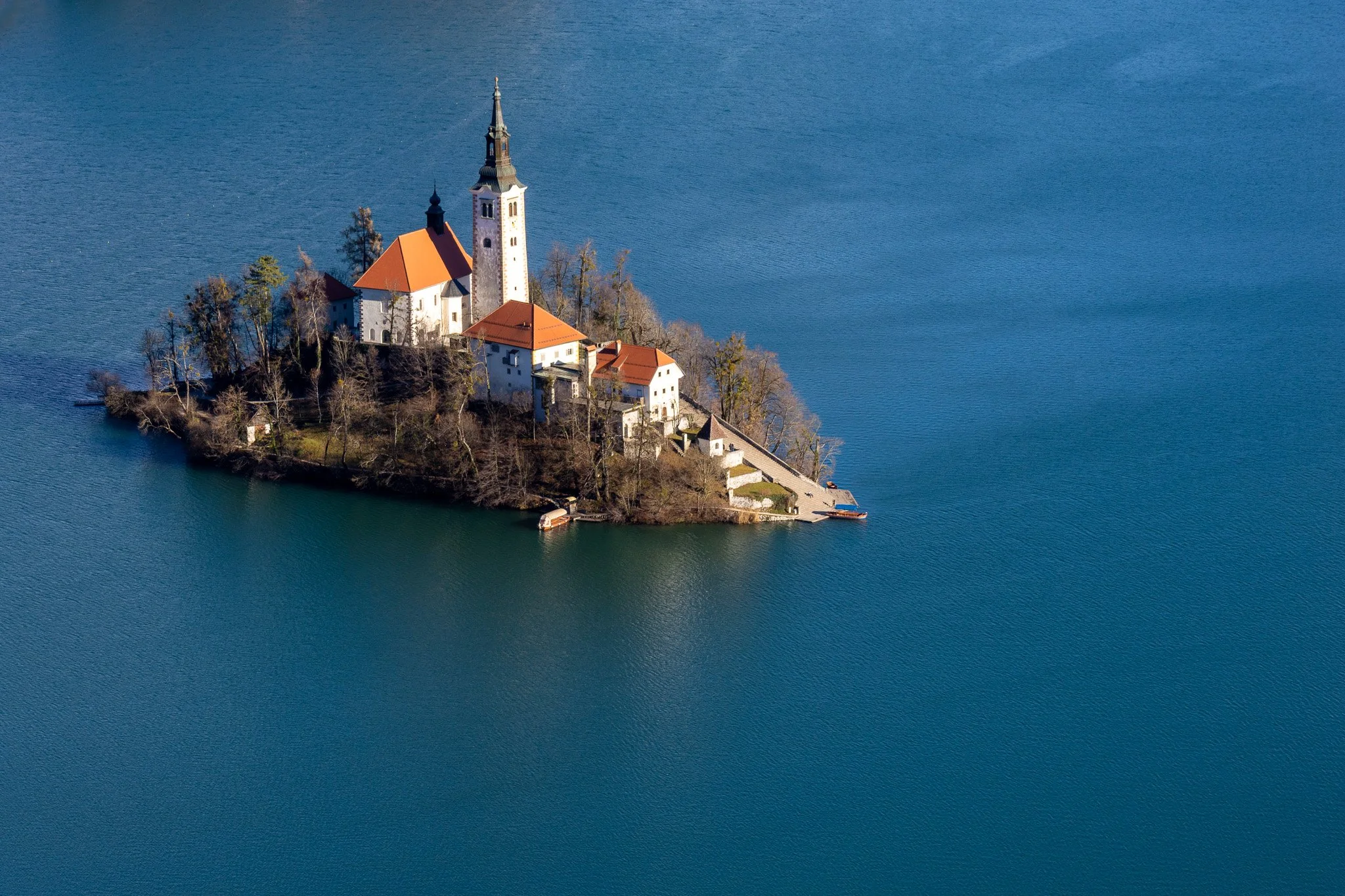 A small island with a church and several buildings surrounded by a lake.
