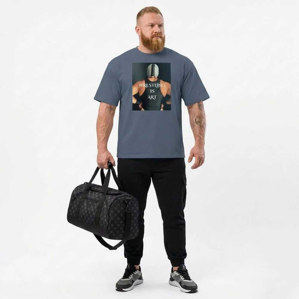 Front view of the Wrestling Is Art oversized tee in faded indigo, styled with a black bag