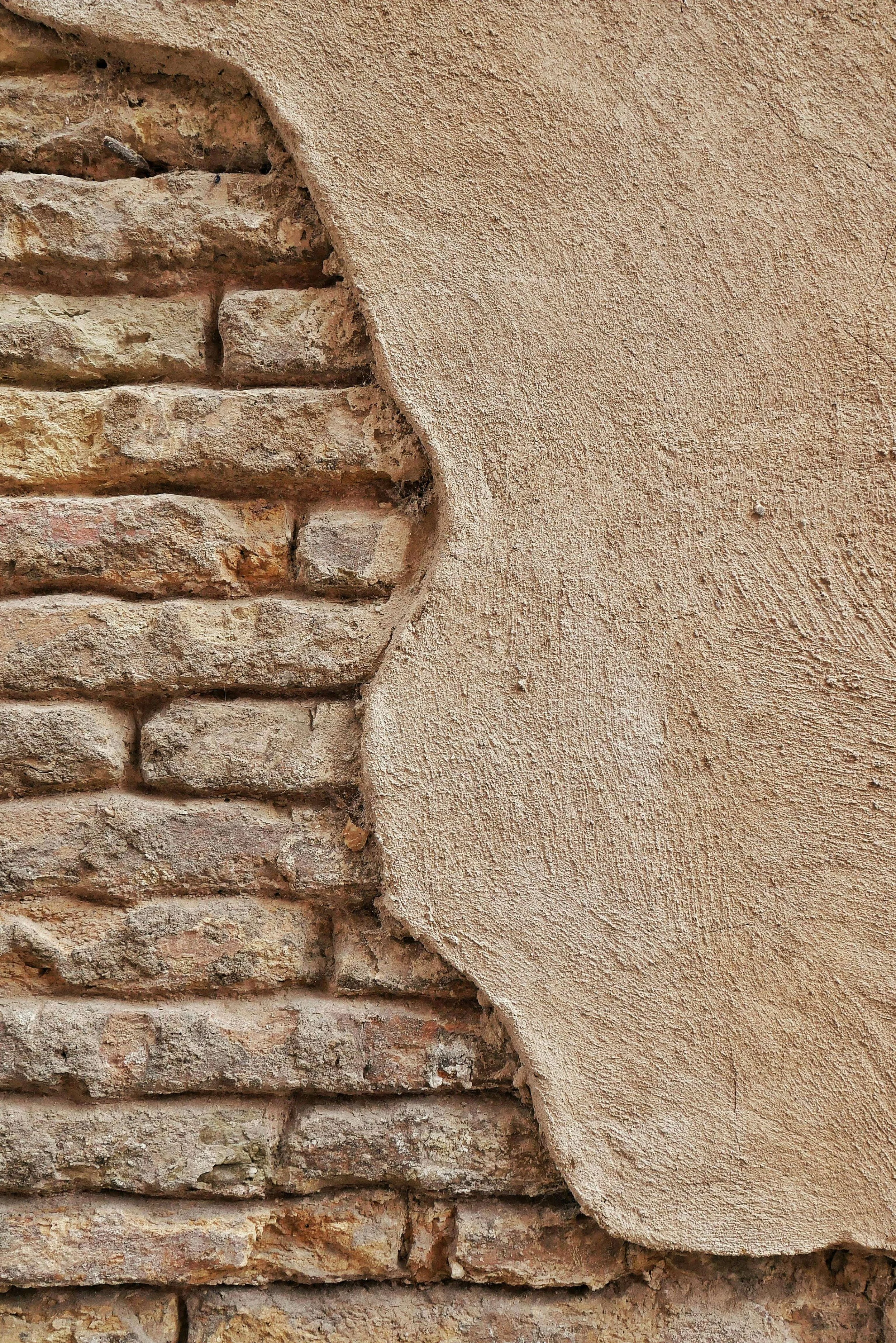 Close-up of a corner where a brick wall meets a textured plaster wall.