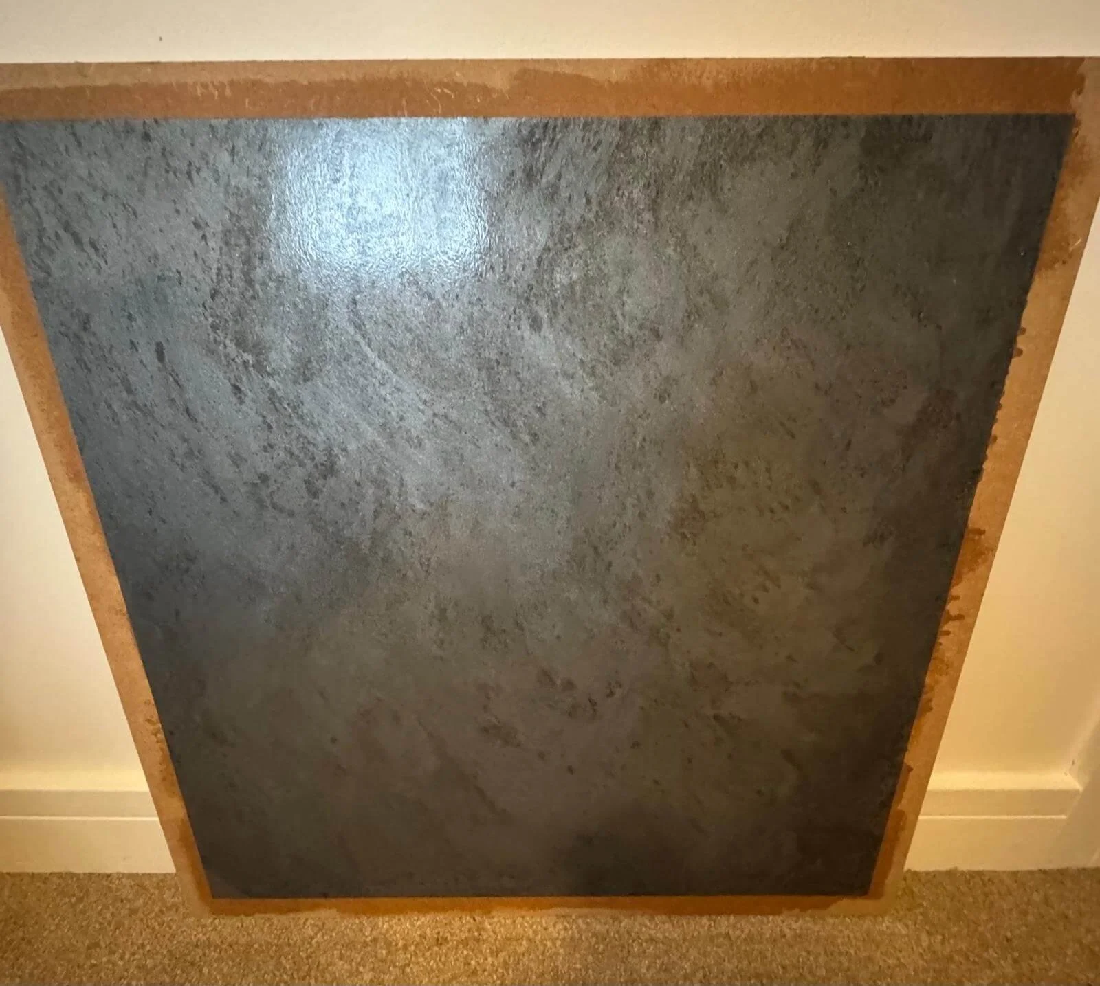 Fallen ceiling tile with silver metallic finish and brown edges on the floor.