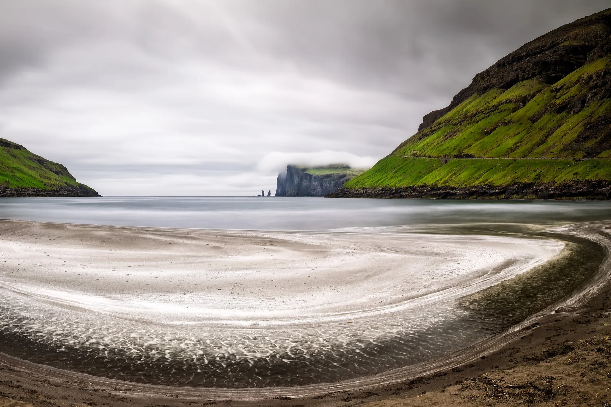 Sort sandstrand med udsigt til klippenålene Risin og Kellingin, Tjornuvik, Faroe Islands