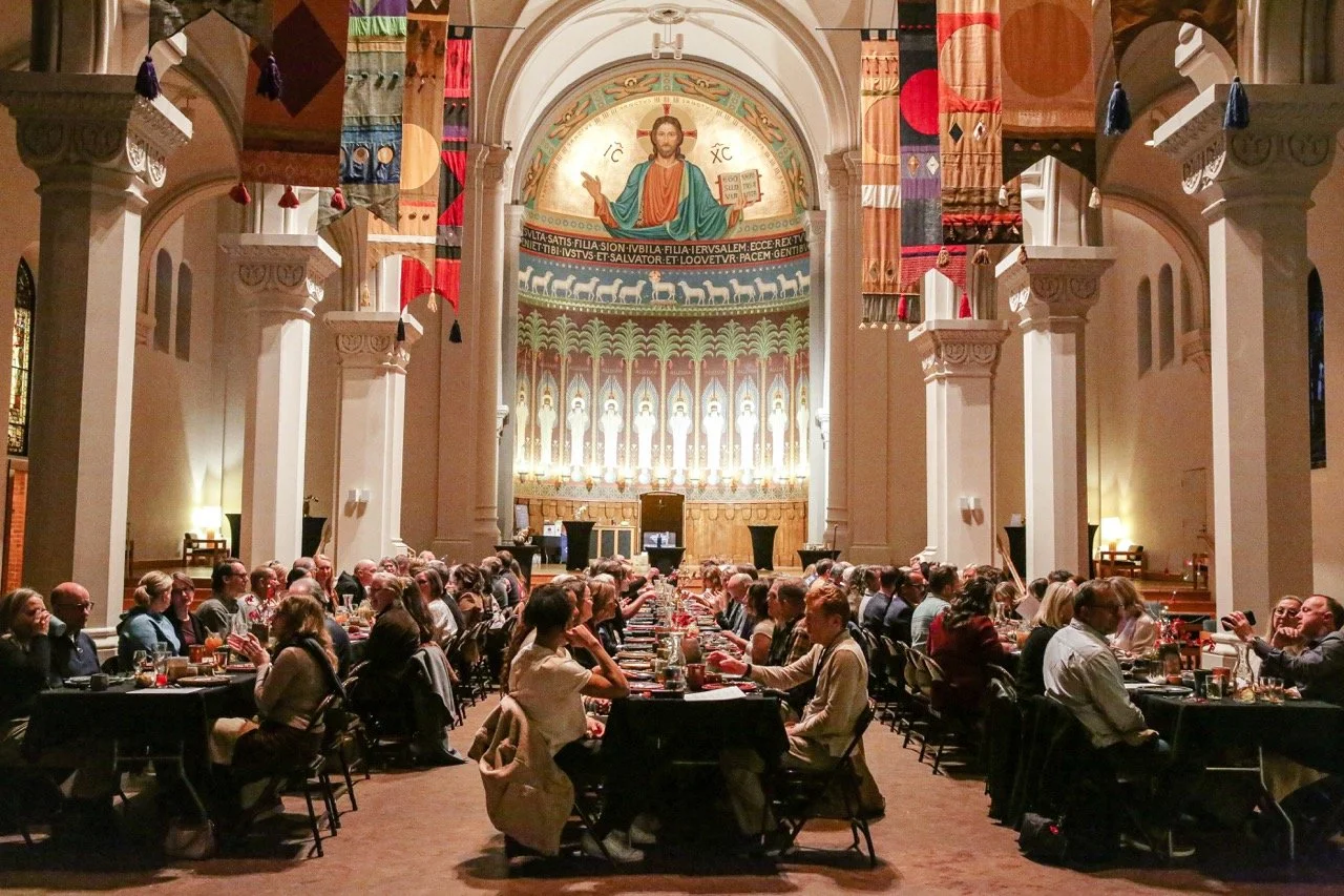 Candlelit communal table set for 180 guests at Story Feast Collective's immersive multi-course harvest dinner at St. John's Abbey monastery in Minnesota — story-driven experiential dining