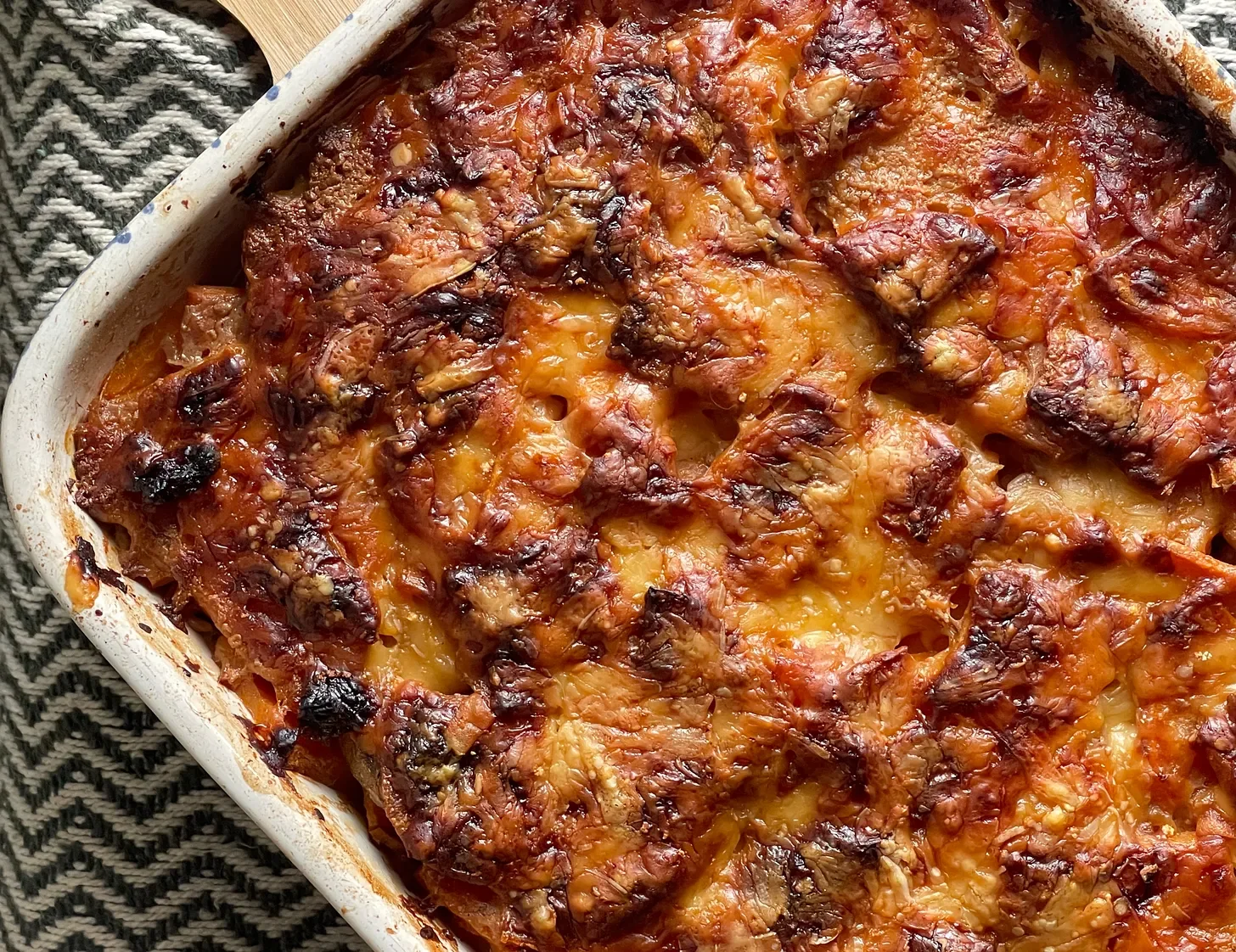 Roux's Chocolate and Cinnamon-Infused Sweet Potato Gratin with golden, bubbly Gruyère cheese in a ceramic baking dish, a Chocolat movie inspired side dish