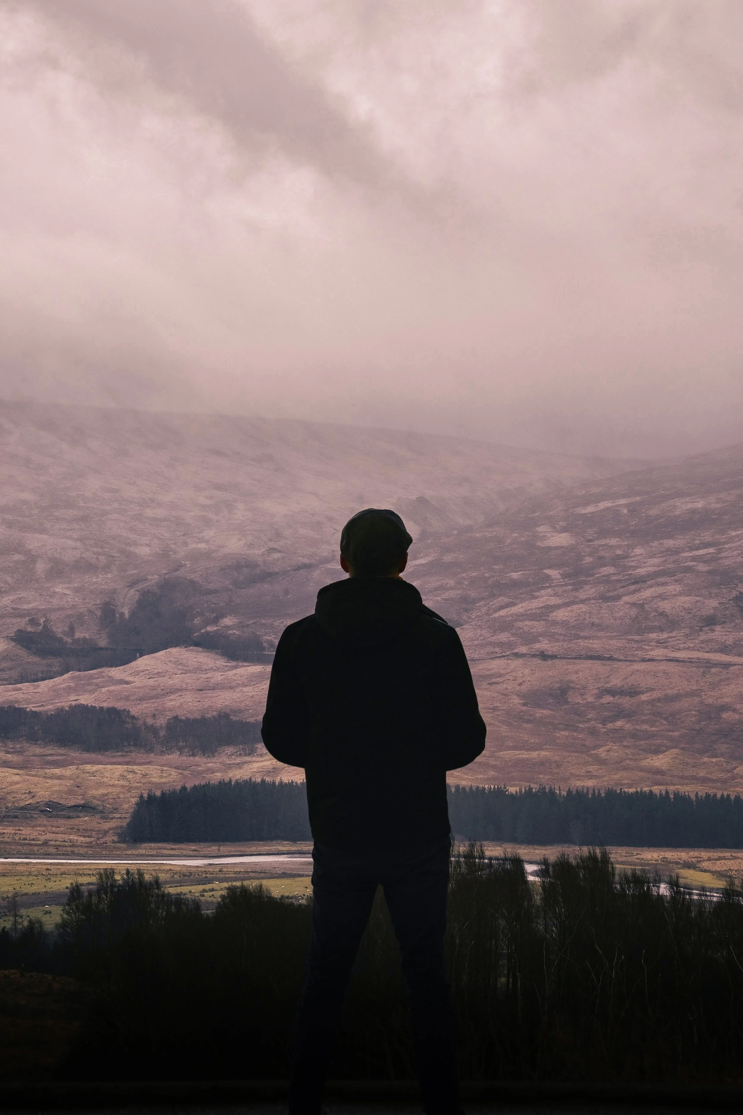 Chris, silhouetted against the backdrop of a large, misty mountain.