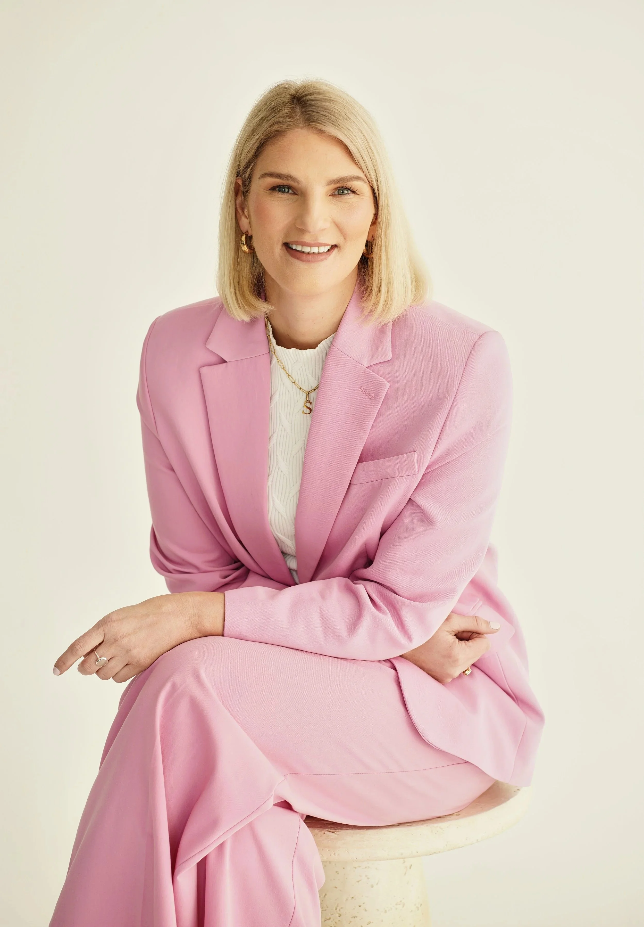 Sarah E Mold career coach in Pink Suit seated on stool