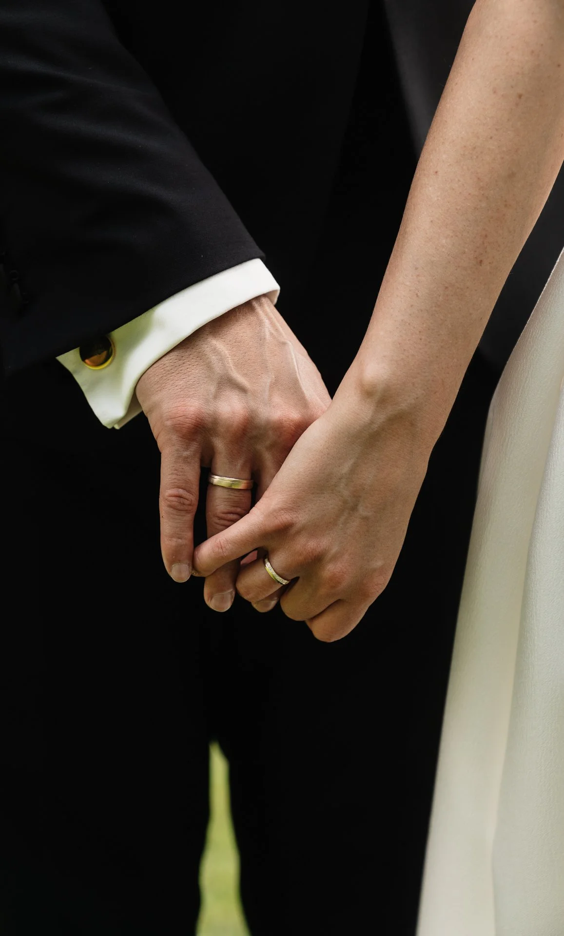 Nahaufnahme von einem Hand- und Fingertouchen eines Paares, das sich an den Händen hält, mit Eheringen, im Zusammenhang mit Hochzeit oder Ehe.