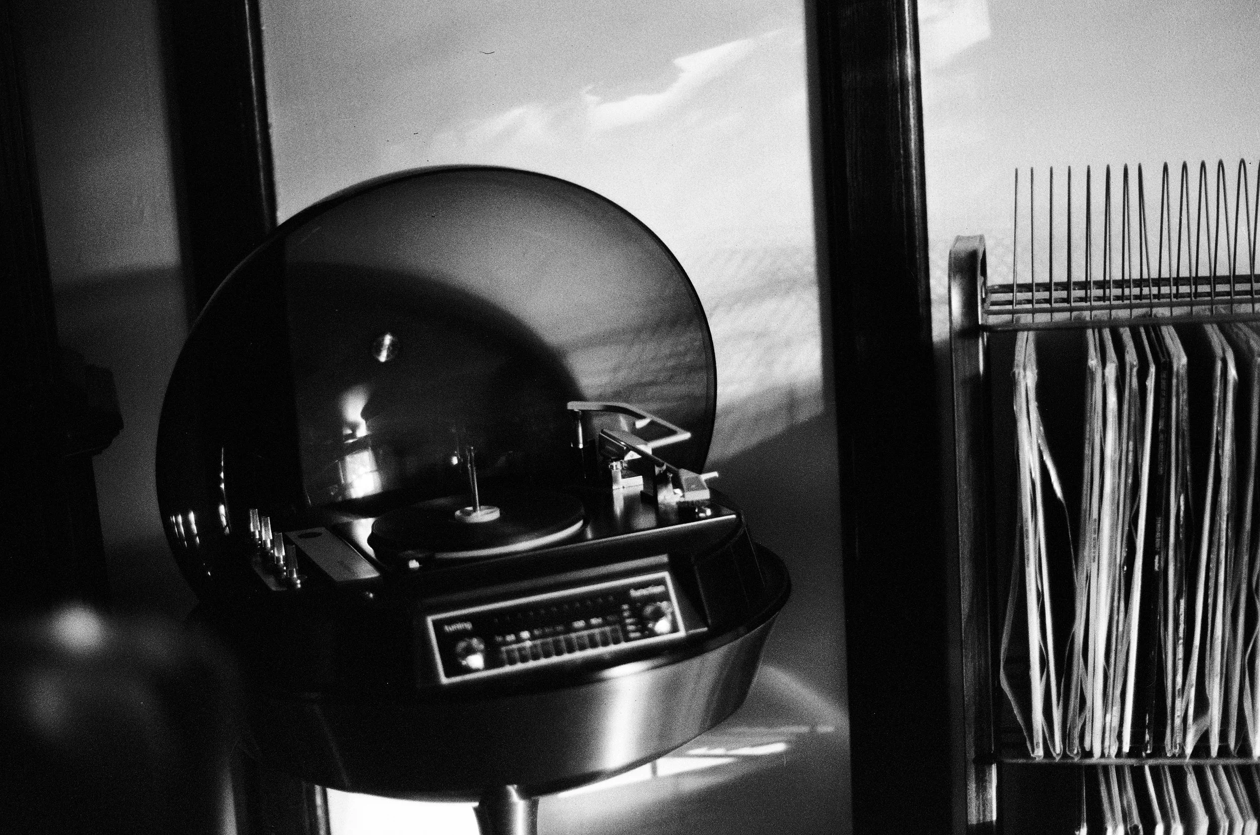 A vintage record player with a record on it, next to a rack holding records or similar materials.