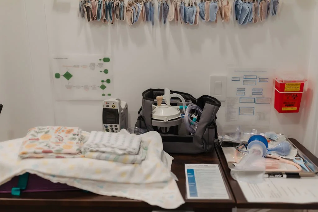 Medical supply table with folded cloths or blankets, medical equipment including a ventilator or breathing apparatus, and various medical tools, in a clinical setting.