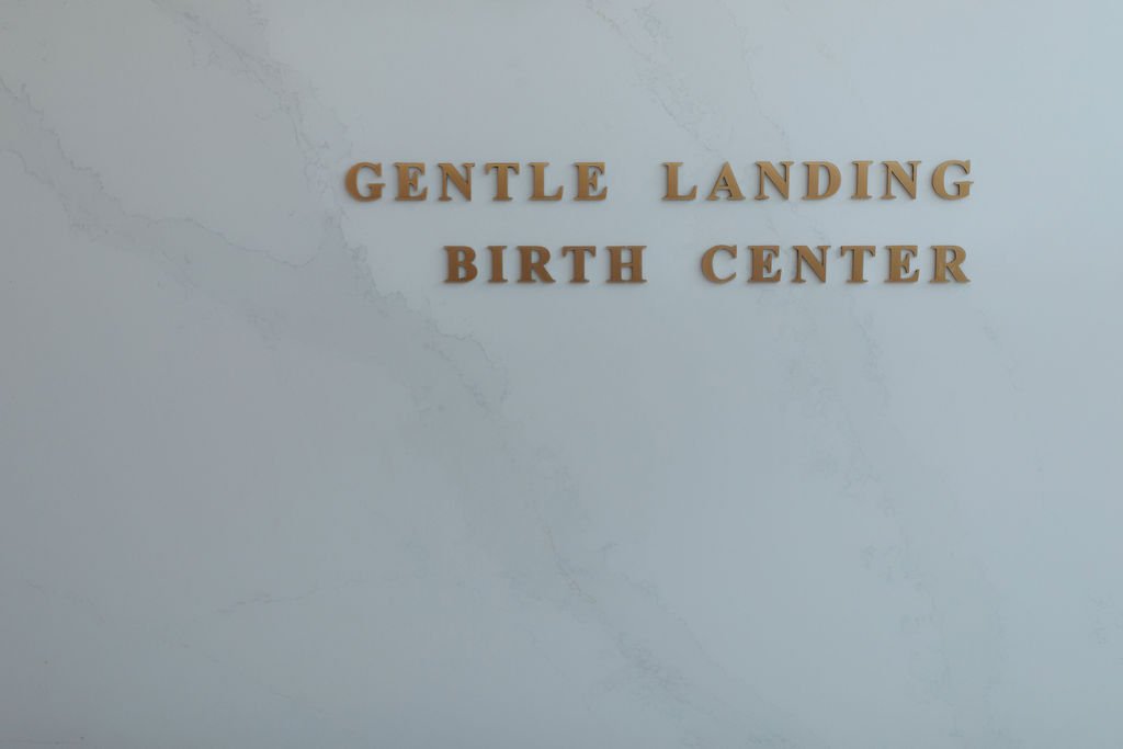 Sign on a wall reading 'Gentle Landing Birth Center' in gold letters.