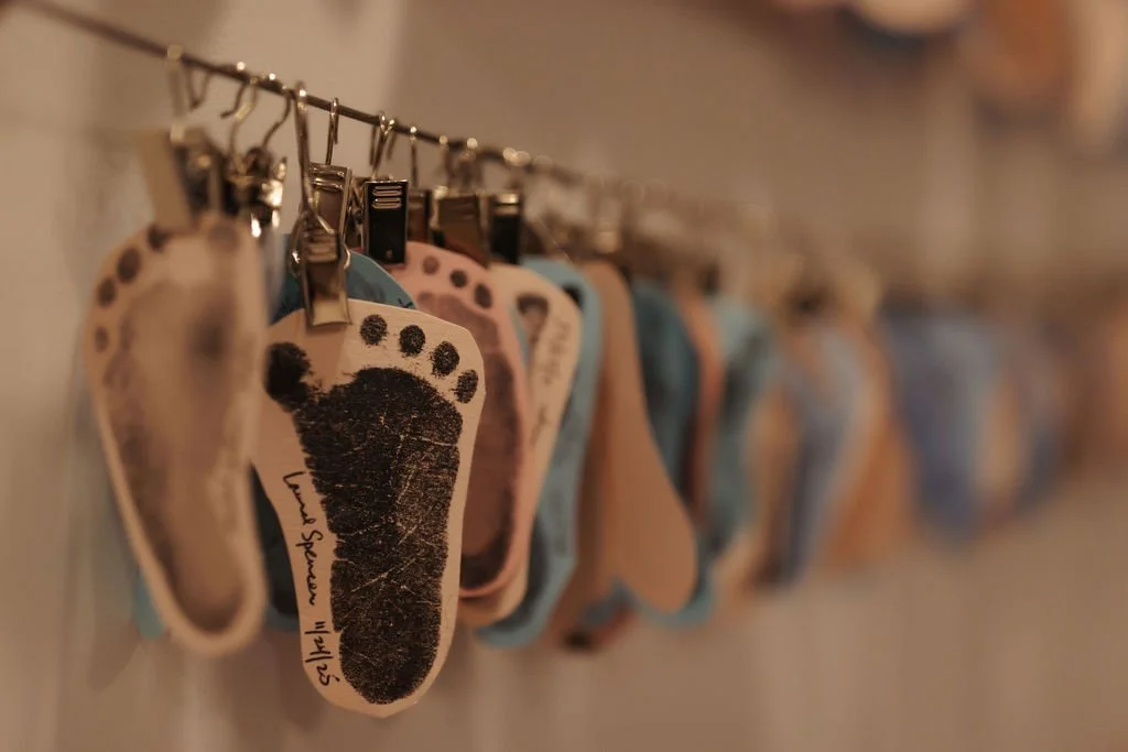 Baby socks hanging on a line, some with paw print designs, in various colors including pink, blue, and beige.
