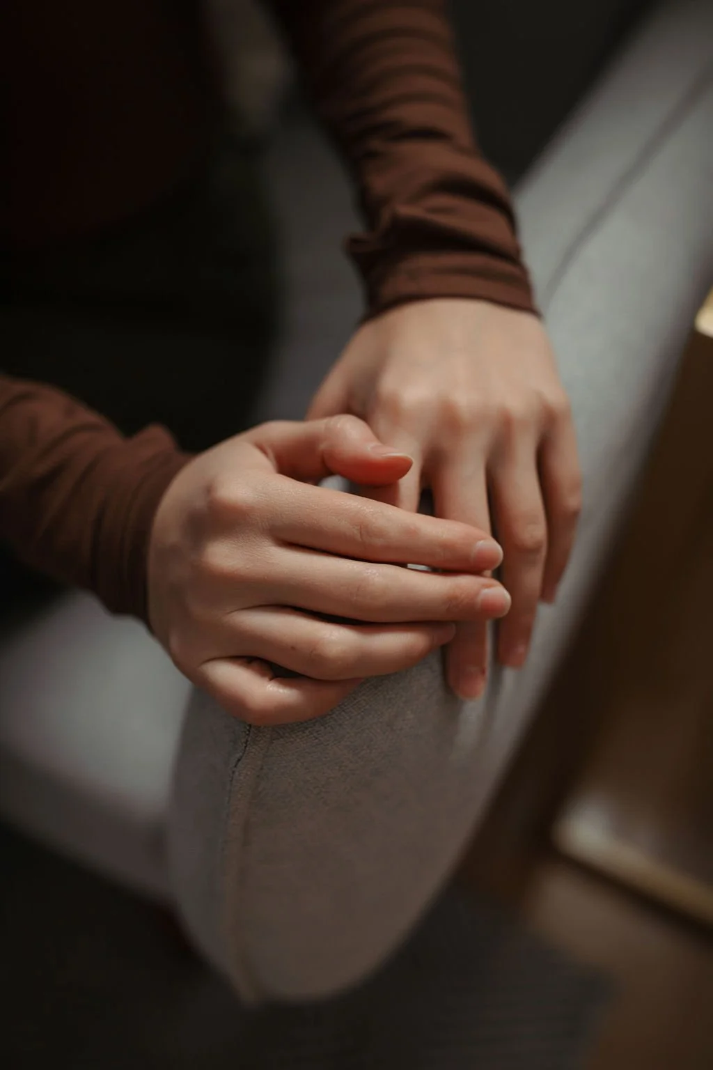 Two people holding hands, sitting on a couch, with one person's hand resting on the other's.