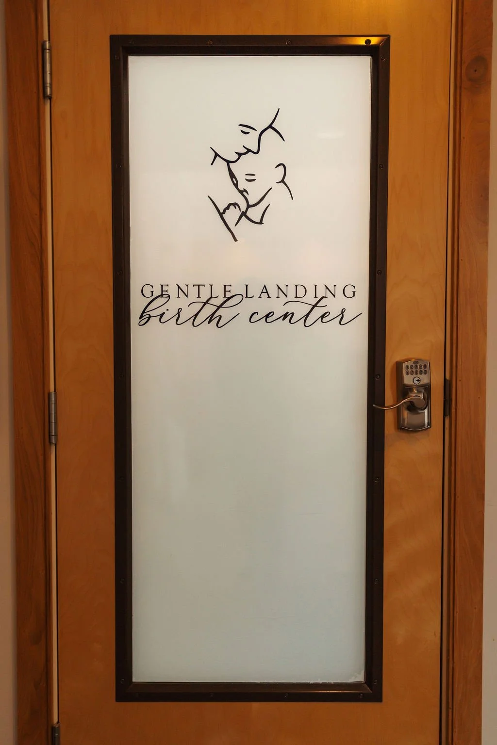 Door with a sign reading 'Gentle Landing Birth Center' and a line drawing of a mother holding her baby.